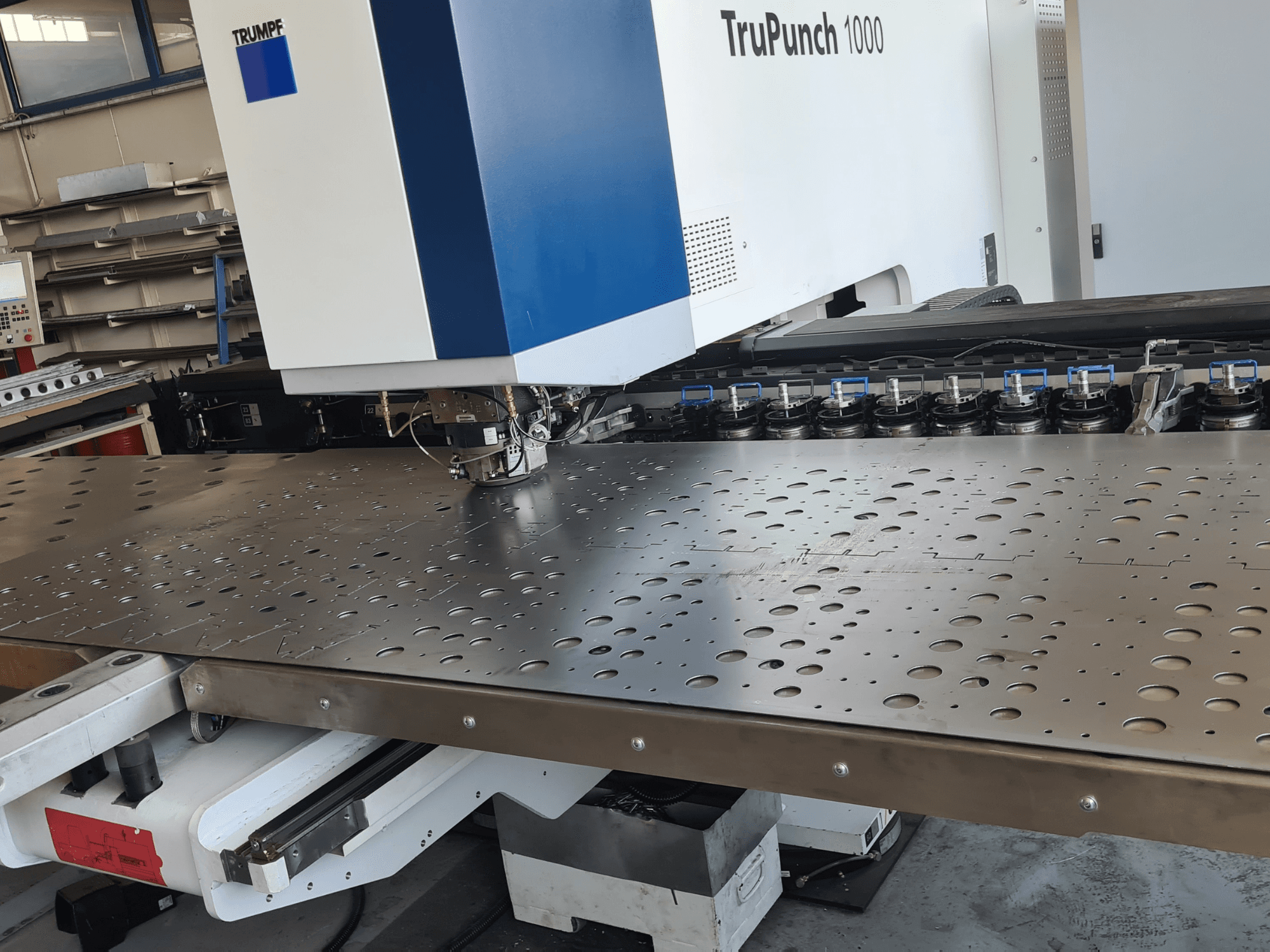 Poinçonneuse CNC TRUMPF TruPunch 1000, vue de face, présentant une tôle perforée et la configuration de l'outil.