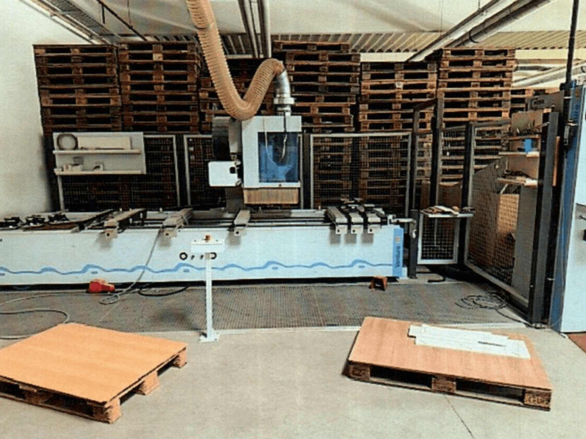 Centre d'usinage du bois CNC Weeke Venture 1M dans un atelier, vue de face avec palettes en bois visibles et installation industrielle.