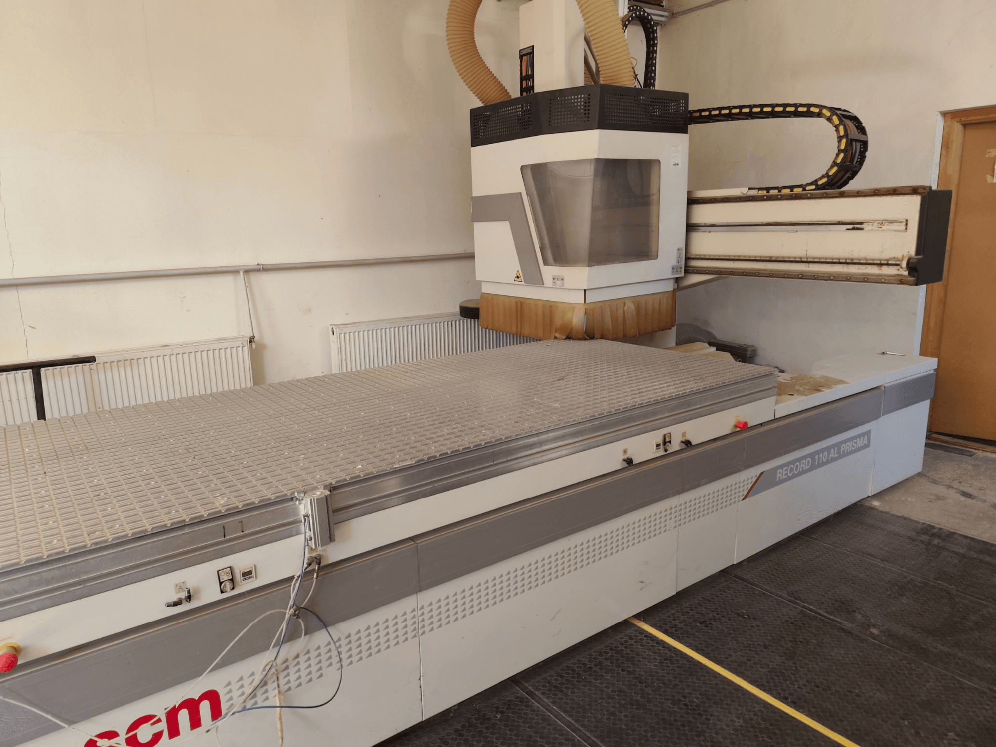 Centre d'usinage CNC pour le bois SCM Record 110AL, vue de profil mettant en valeur la grande table de travail et la tête de fraisage.