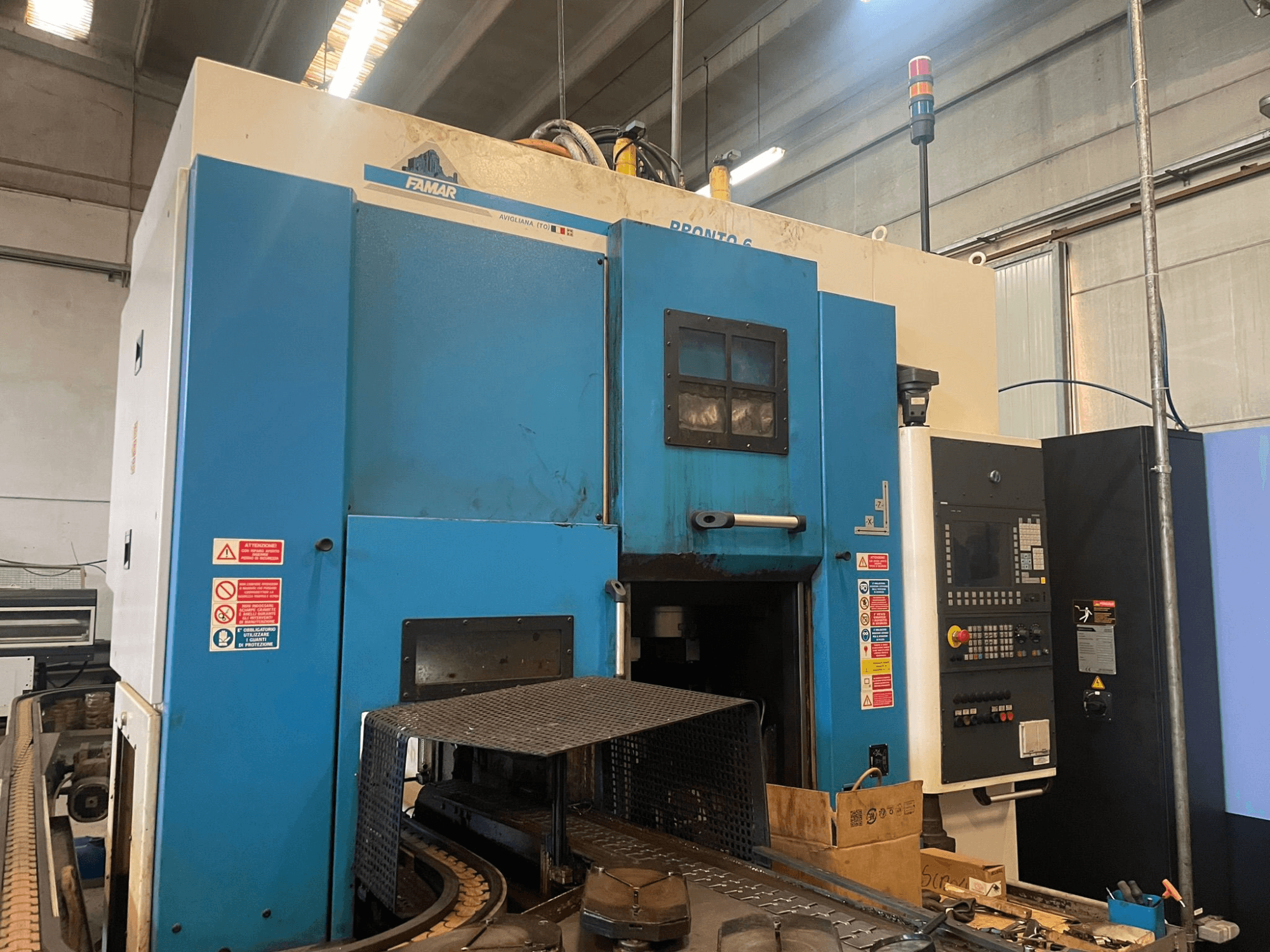 Tour vertical Famar Pronto 6 dans un atelier, vue latérale, montrant le panneau de commande, les caractéristiques opérationnelles et les étiquettes de sécurité.