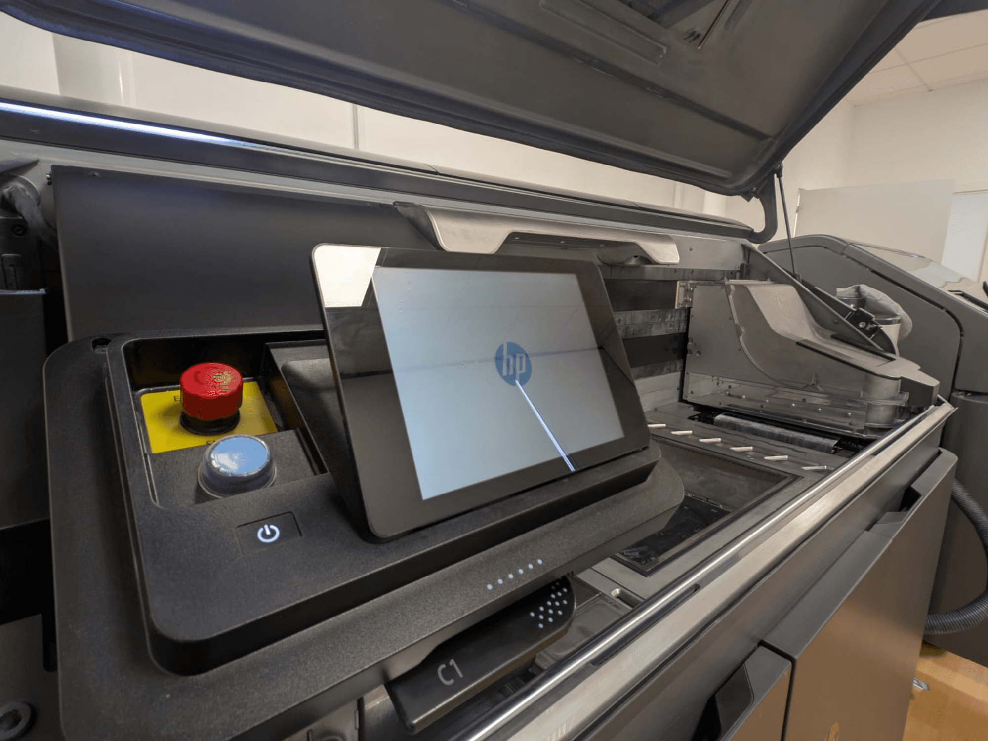 Panneau de commande de l'imprimante HP montrant une tablette, des boutons rouges et bleus, et une vue latérale des composants intérieurs de l'imprimante.