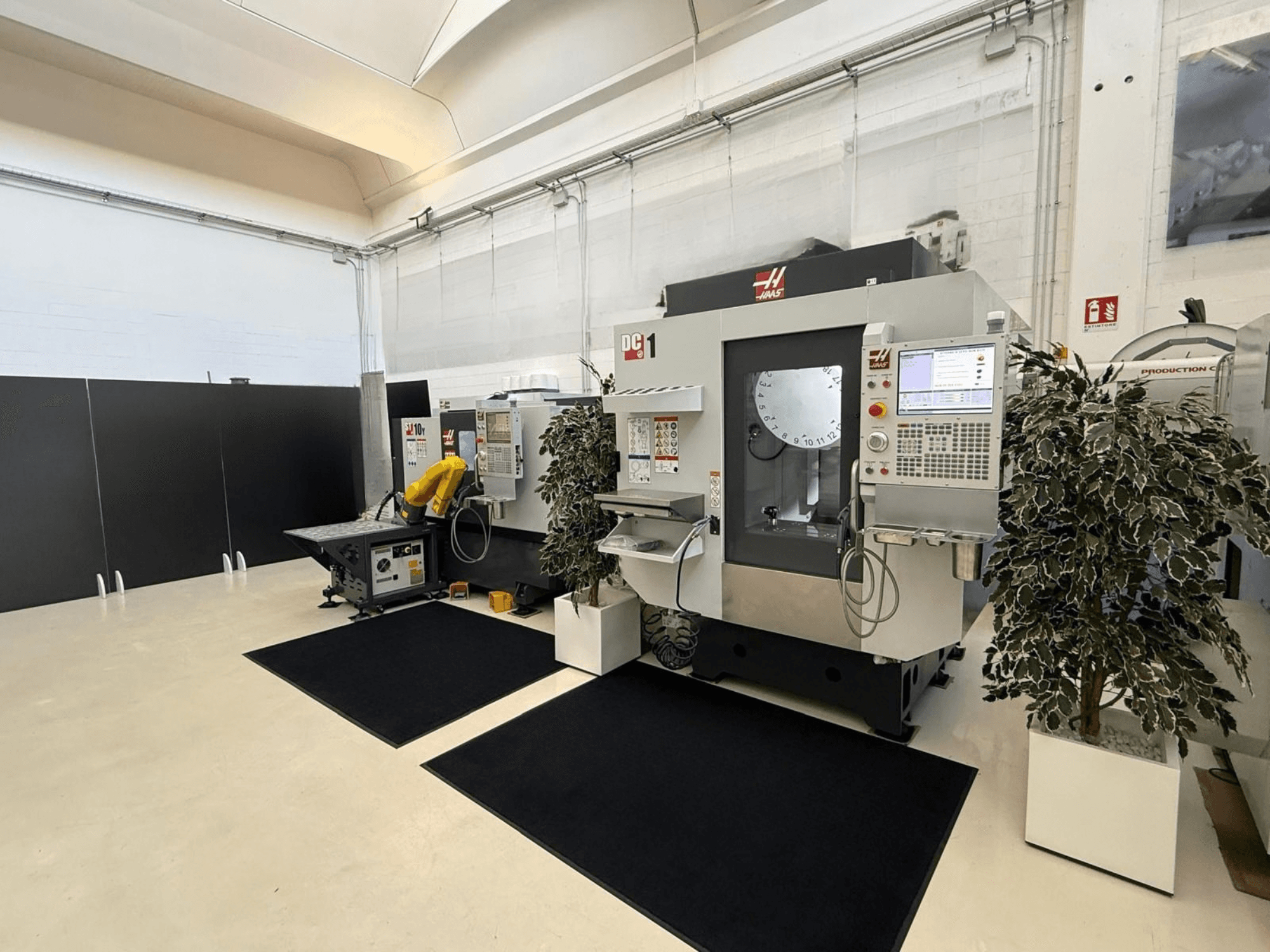 Vue de face d'un centre d'usinage vertical HAAS DC-1 dans un espace de travail propre, avec son panneau de commande à écran tactile et les installations environnantes.