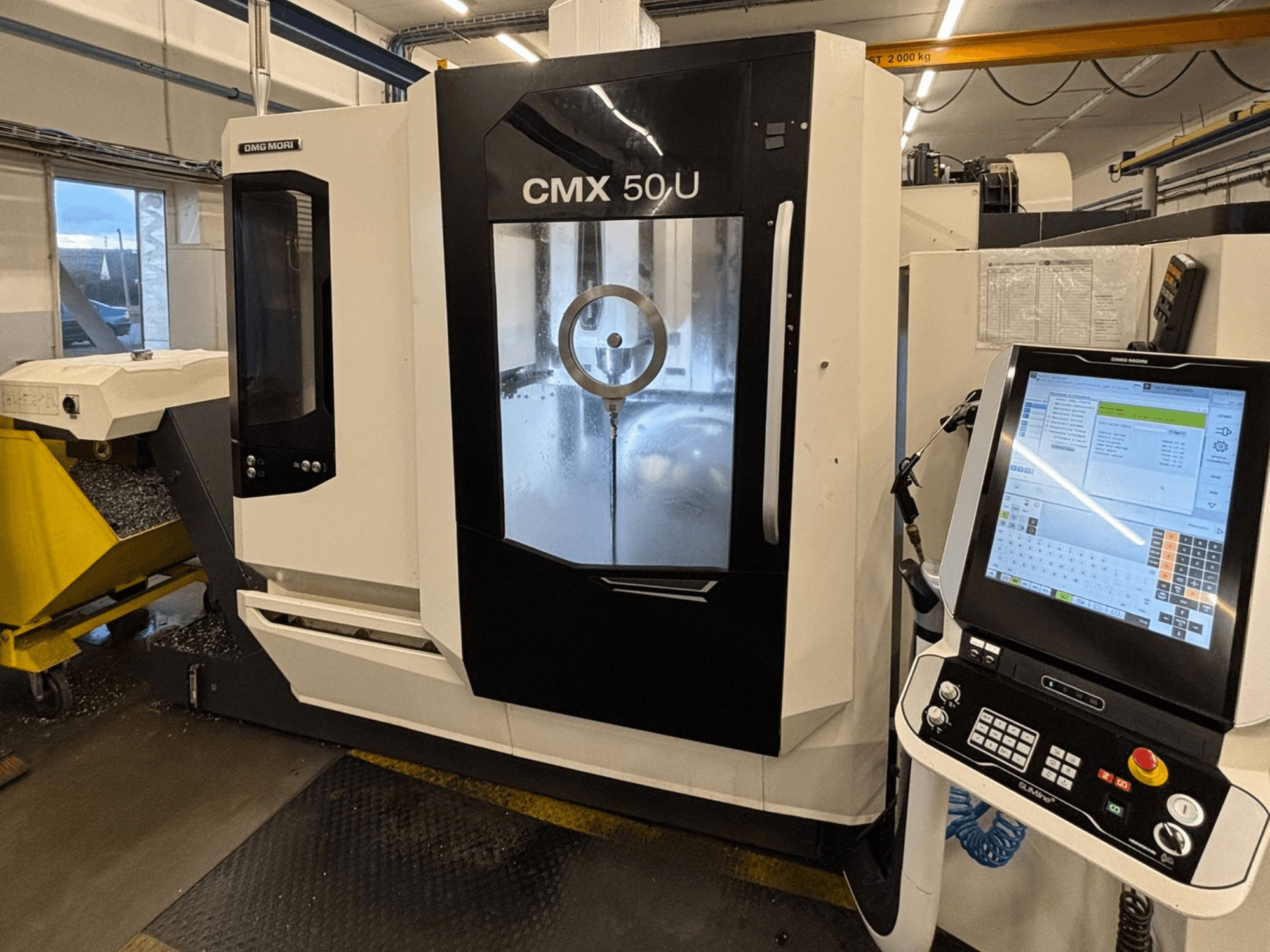 Centre d'usinage vertical DMG MORI CMX 50 U, vue de face avec panneau de commande et écran en verre, présentant la mécanique interne.