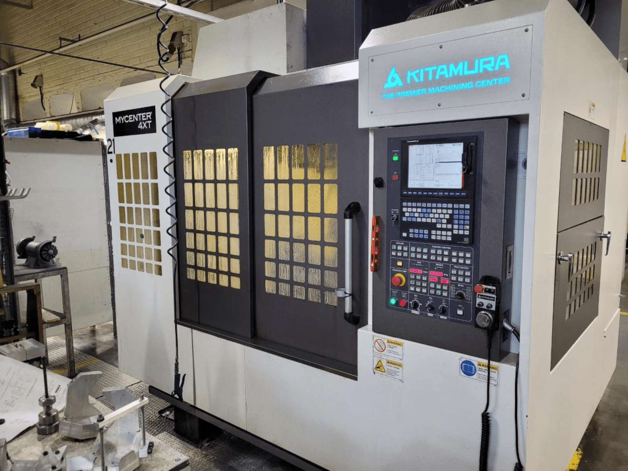 Vue verticale d'un centre d'usinage Kitamura Mycenter-4XT, avec panneau de commande et marquage lumineux.