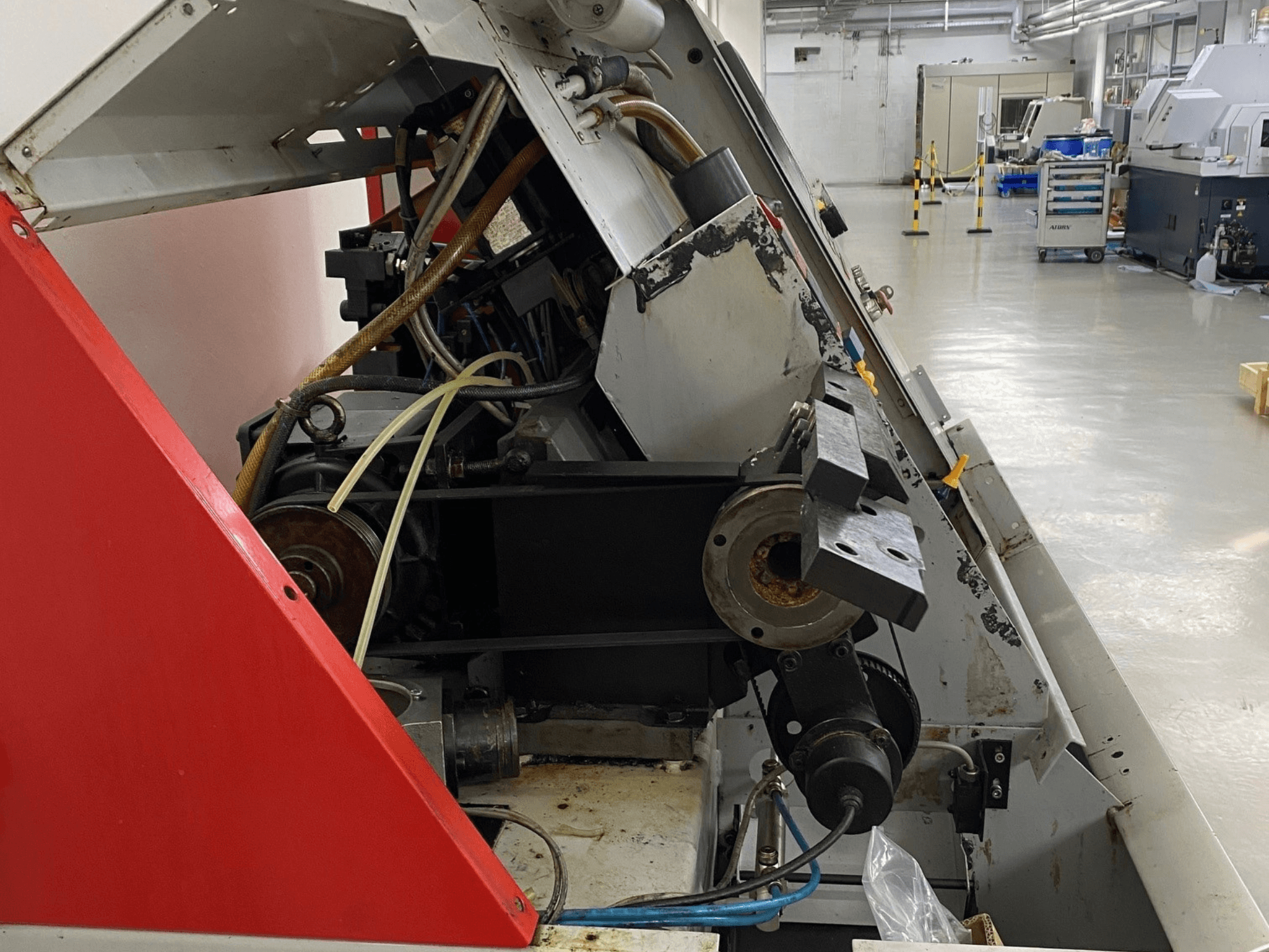 Tour horizontal EMCO Emcoturn 325, vue latérale montrant les composants d'entraînement et le système hydraulique dans un environnement industriel.