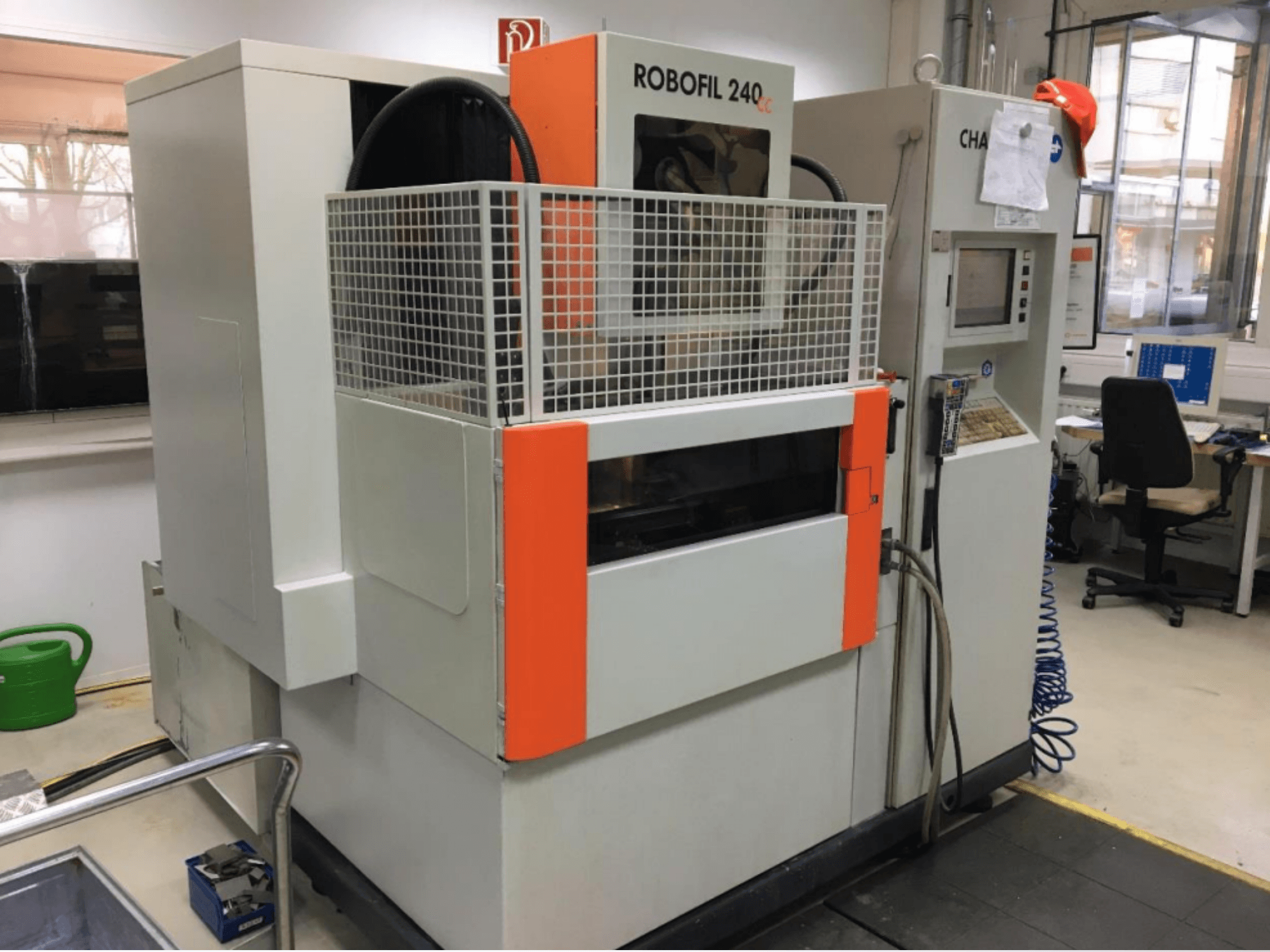Vue de face d'une machine d'électroérosion à fil CHARMILLES ROBOFIL 240 CC, équipée d'une grille de protection et d'un panneau de commande, installée dans un atelier.