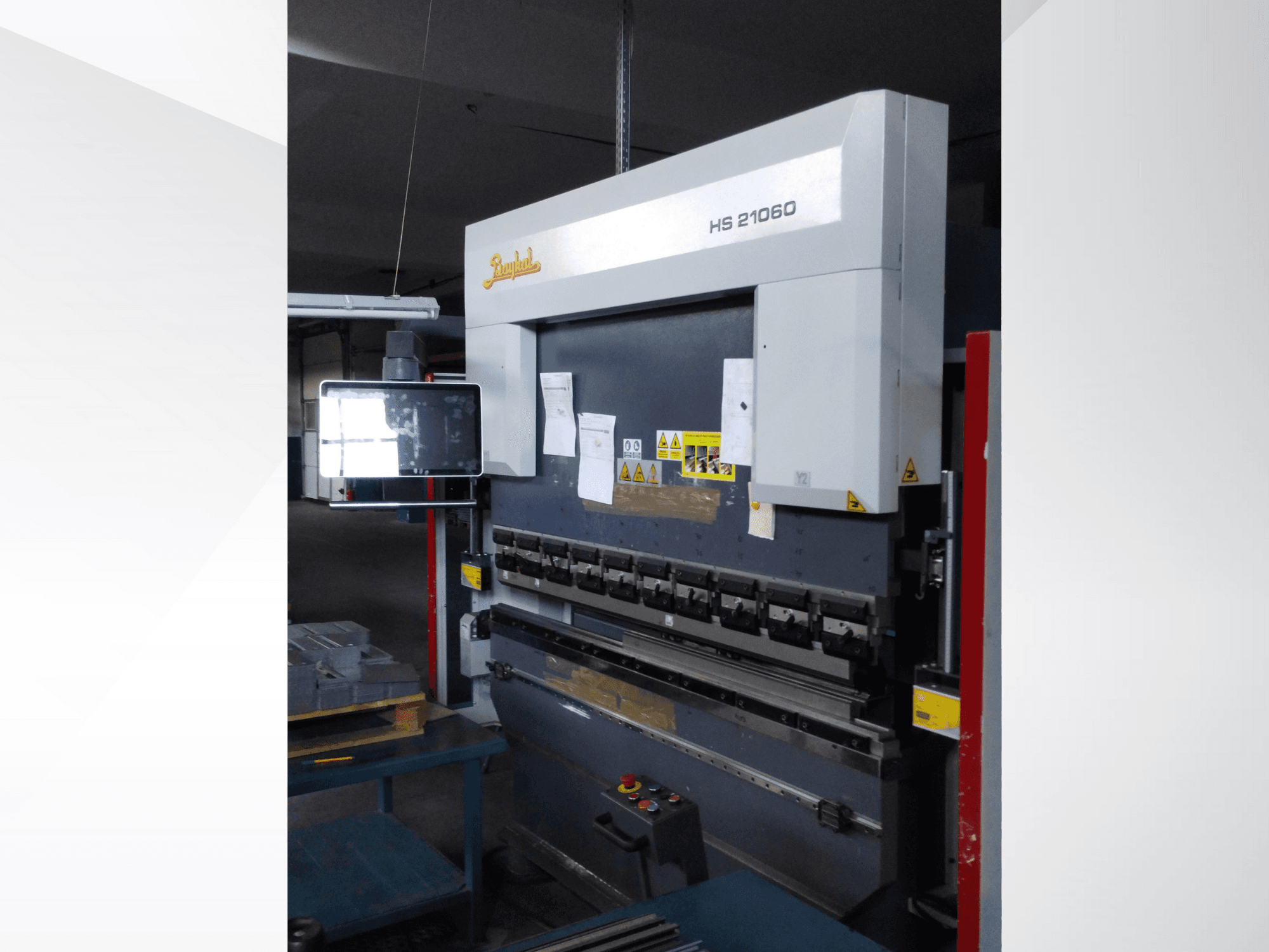 Presse plieuse Beyeler HS 21060, vue de face, montrant des commandes, un écran d'affichage et des étiquettes d'avertissement dans un atelier.