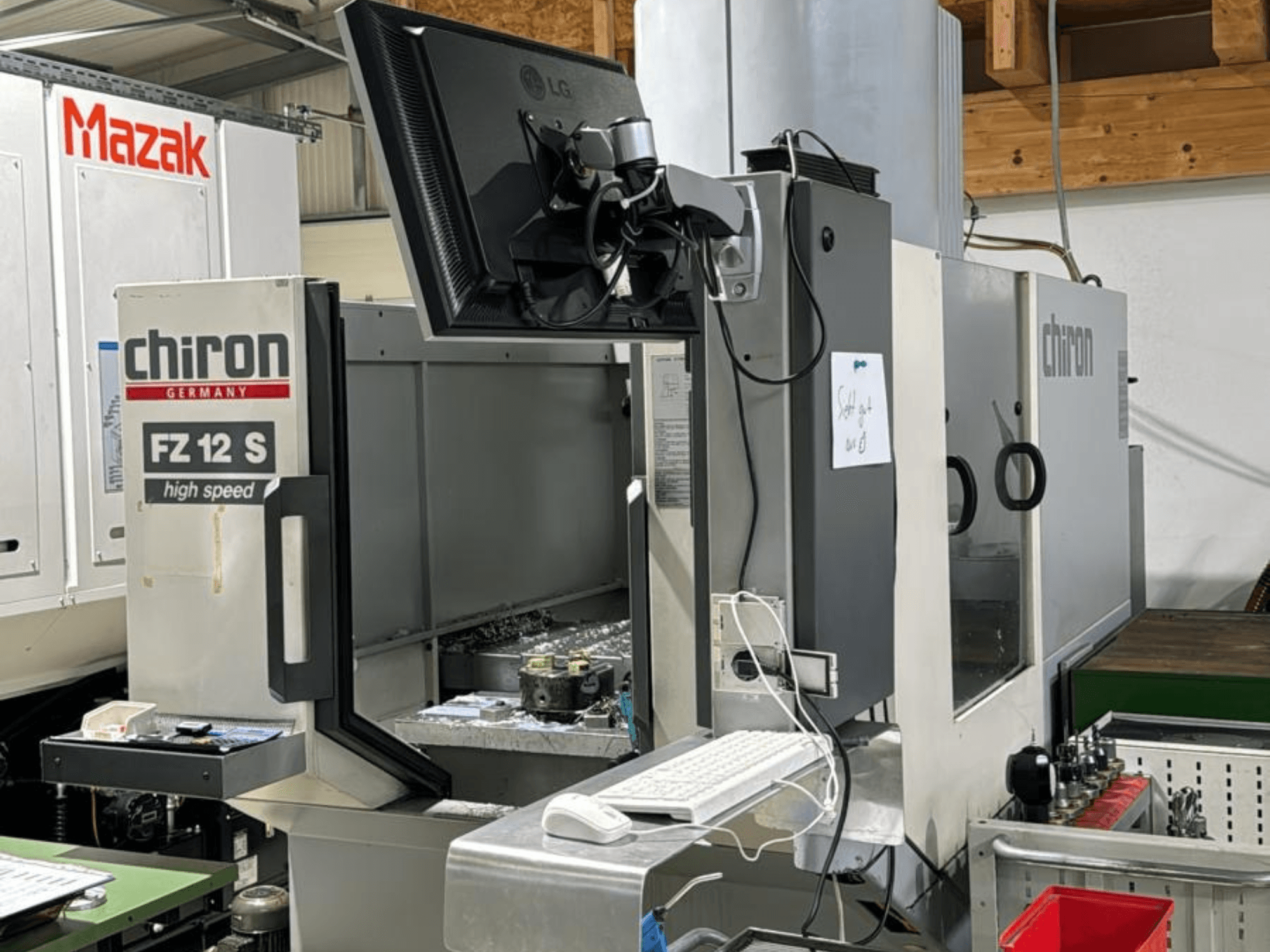 Vue verticale du centre d'usinage à grande vitesse CHIRON FZ 12 S avec écran de contrôle et débris du processus d'usinage.