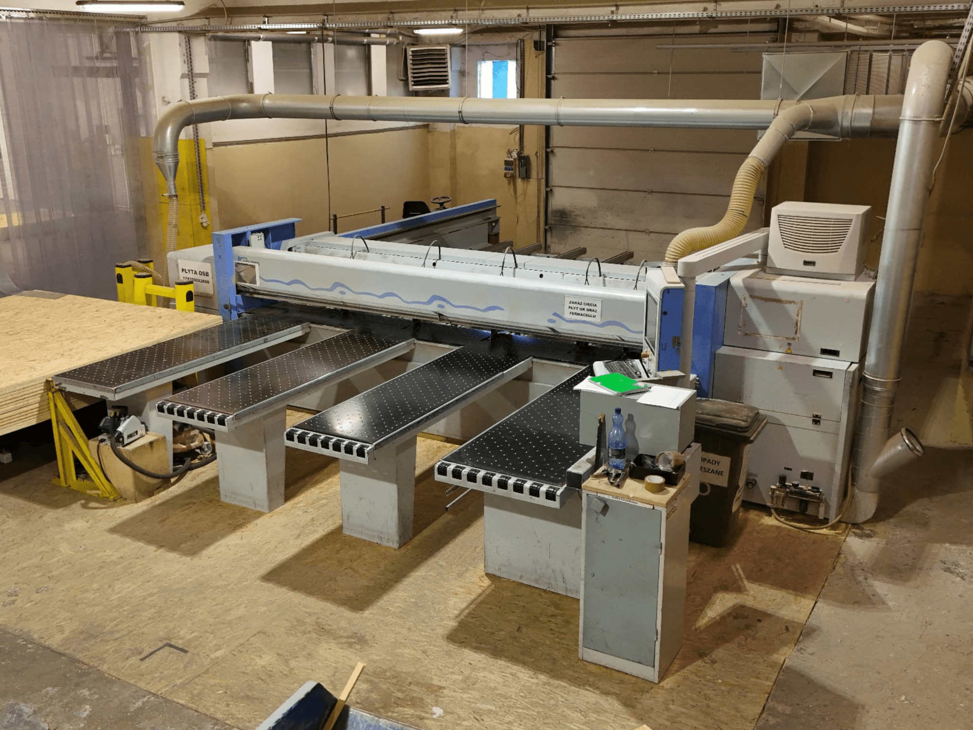 Scie à panneaux HOLZMA HPP 350/43/38 dans un atelier, vue de dessus, montrant la zone de coupe et les tables d'appui.