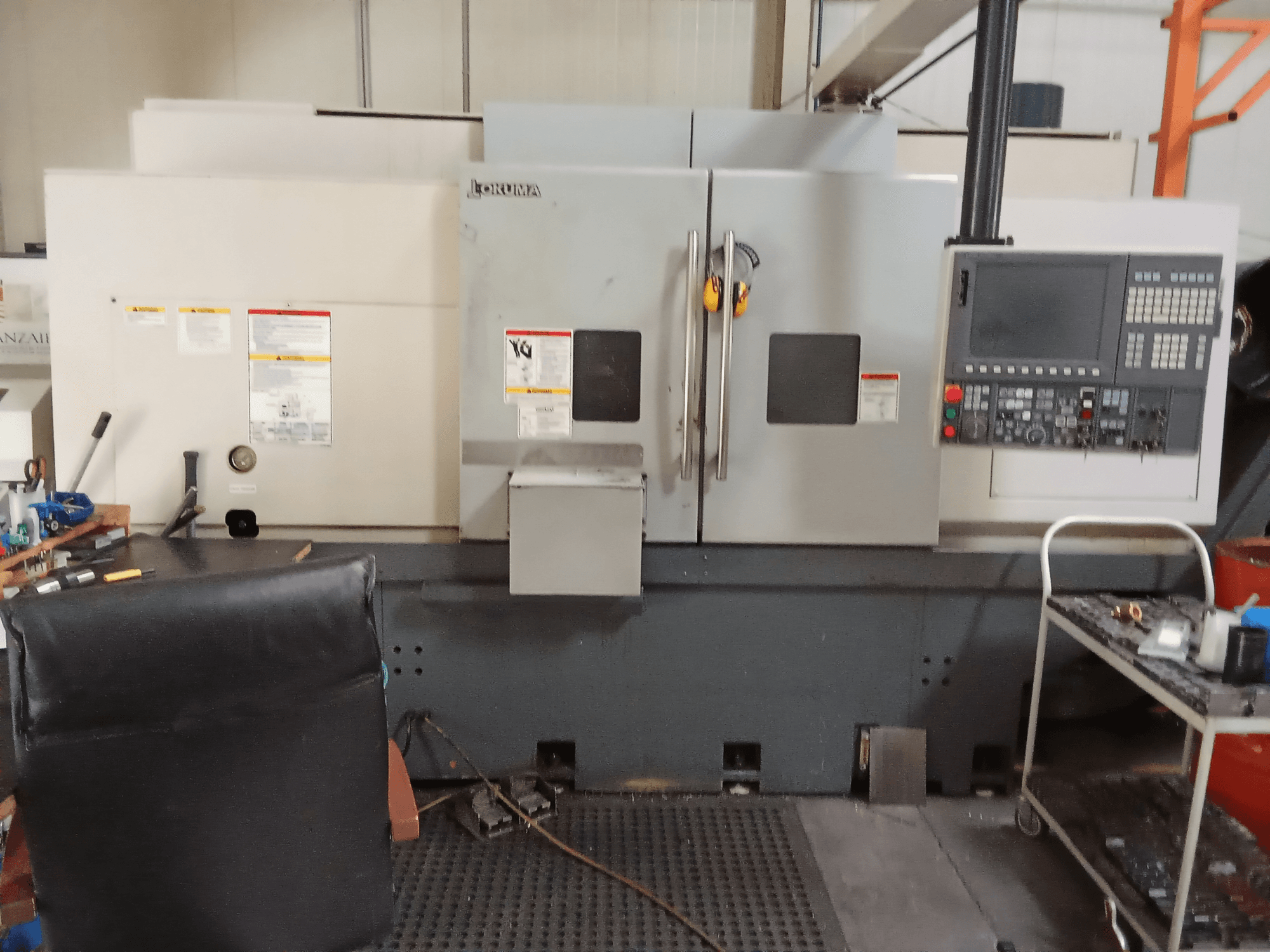 Tour horizontal Okuma Genos L300 E-M en vue de face, montrant le panneau de commande et les deux portes, dans un environnement d'atelier.