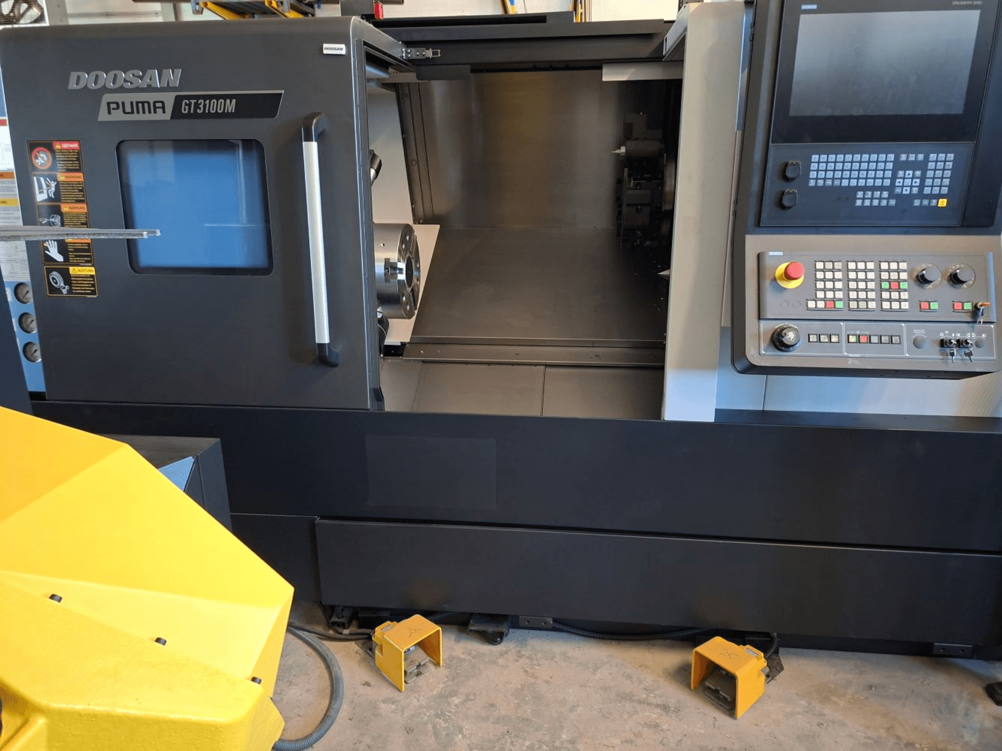 Tour horizontal DOOSAN Puma GT 3100 M en vue de face, montrant le panneau de commande, la tourelle ouverte et l'espace de travail intérieur.