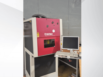 Station de travail laser Trotec rouge, vue de face, équipée d'un écran et d'un clavier.