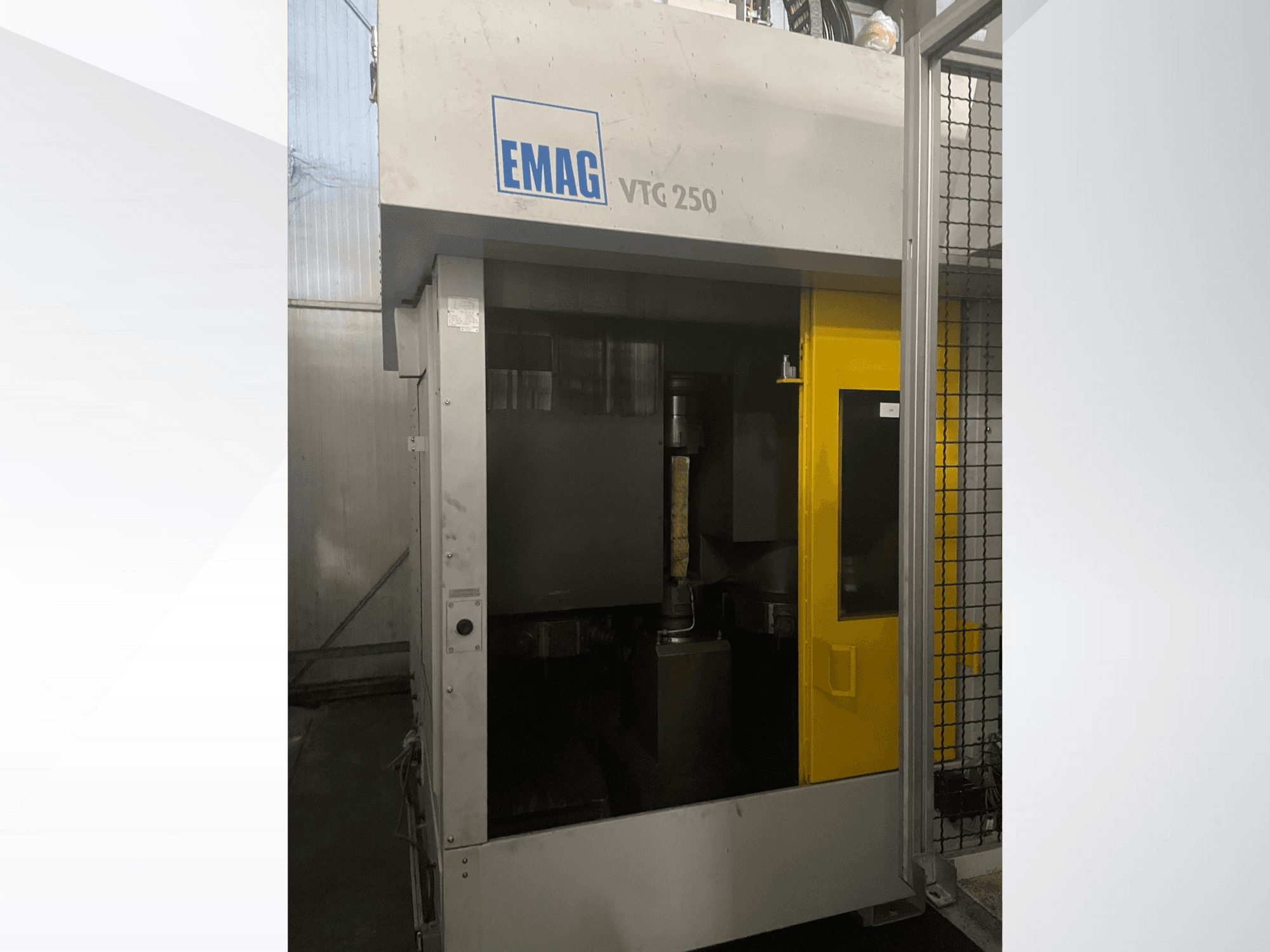 Centre d'usinage vertical EMAG VTC 250 en vue de face, avec une porte jaune et un outil de coupe visible à l'intérieur de la chambre.