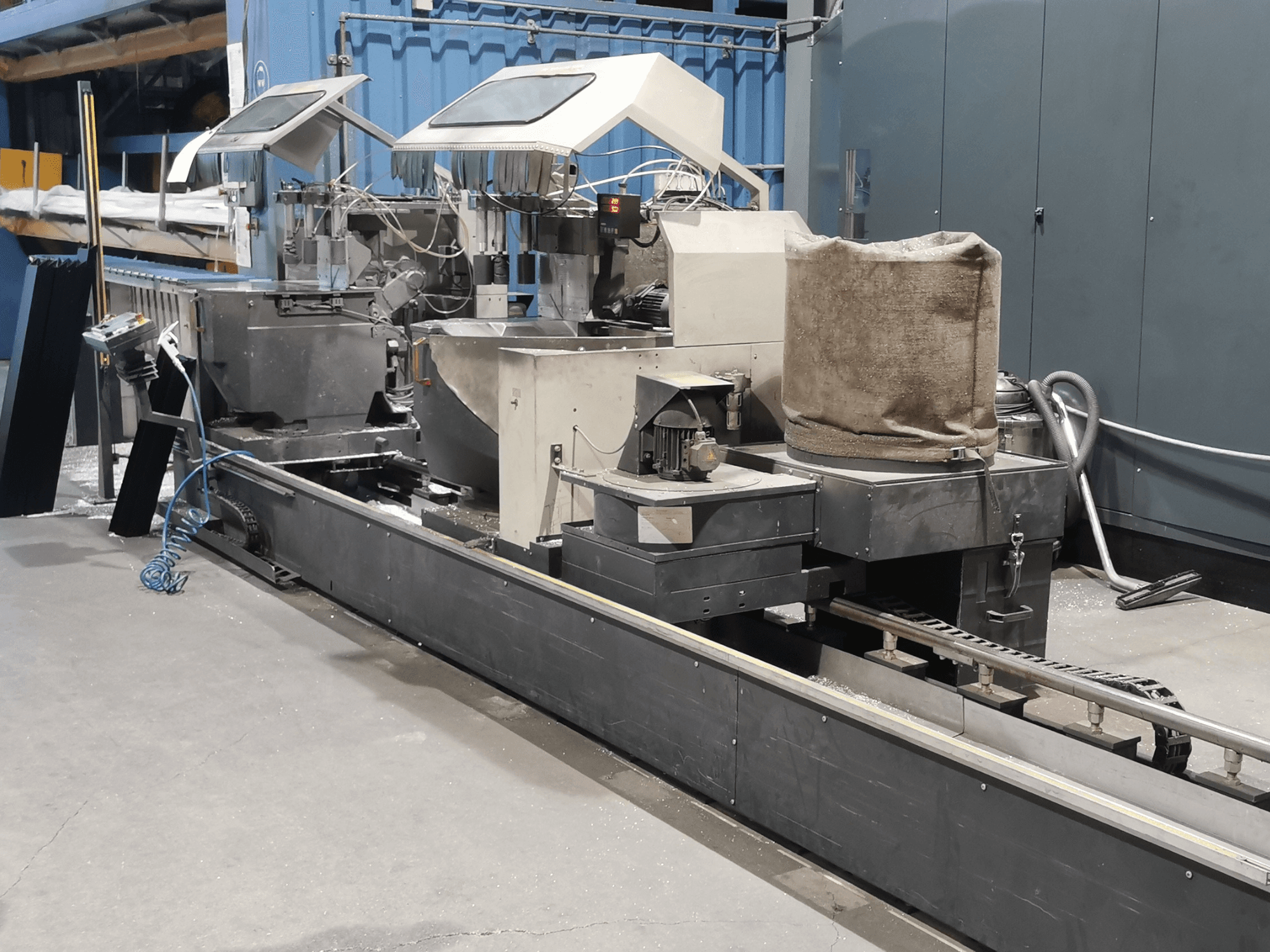 Machine de traitement industriel vue de côté, comprenant des trémies, un convoyeur à bande et un panneau de commande, dans une usine.