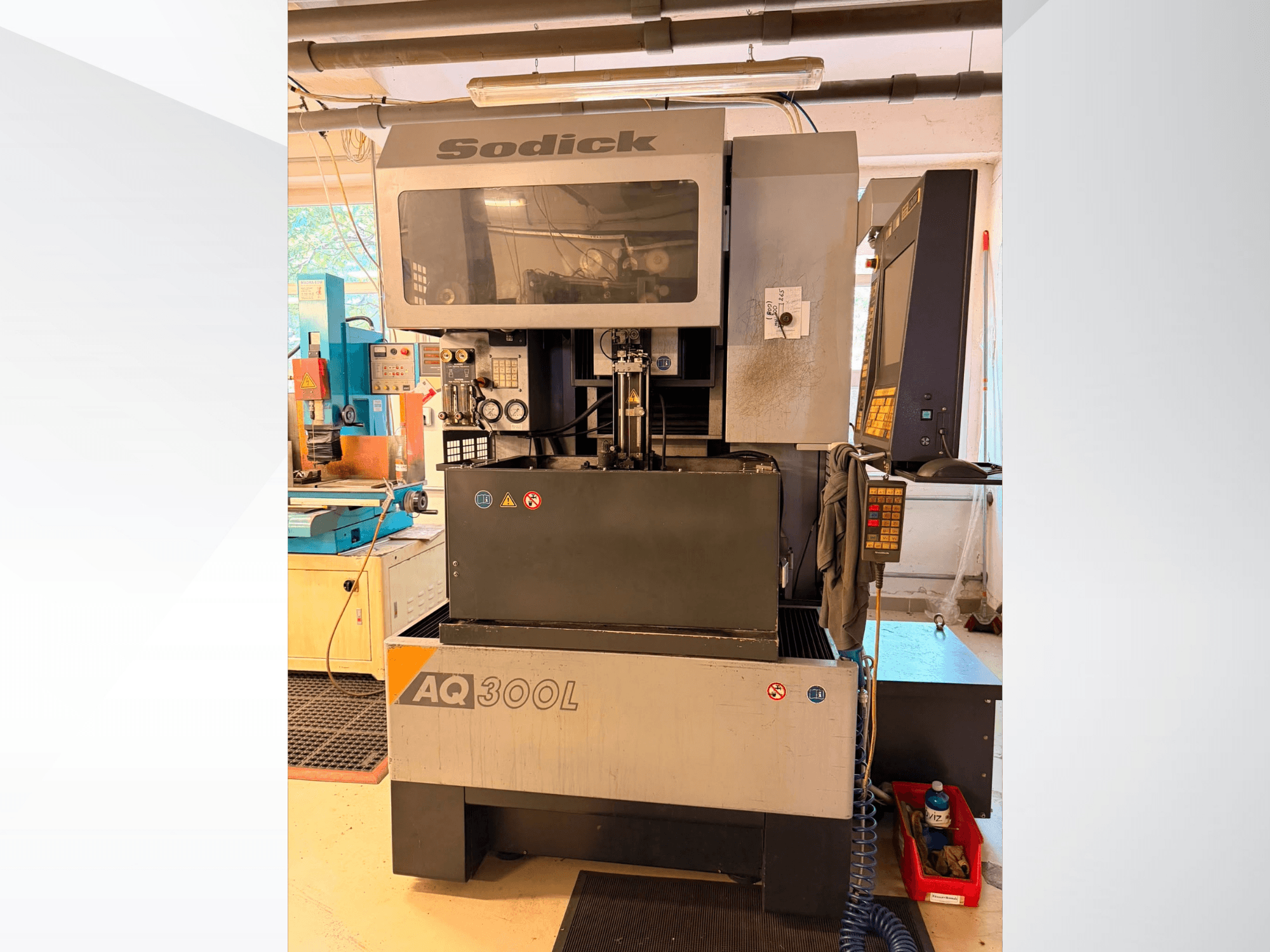 Machine d'électroérosion à fil Sodick AQ300L, vue de face, montrant le panneau de commande, la zone de travail et les voyants de sécurité.