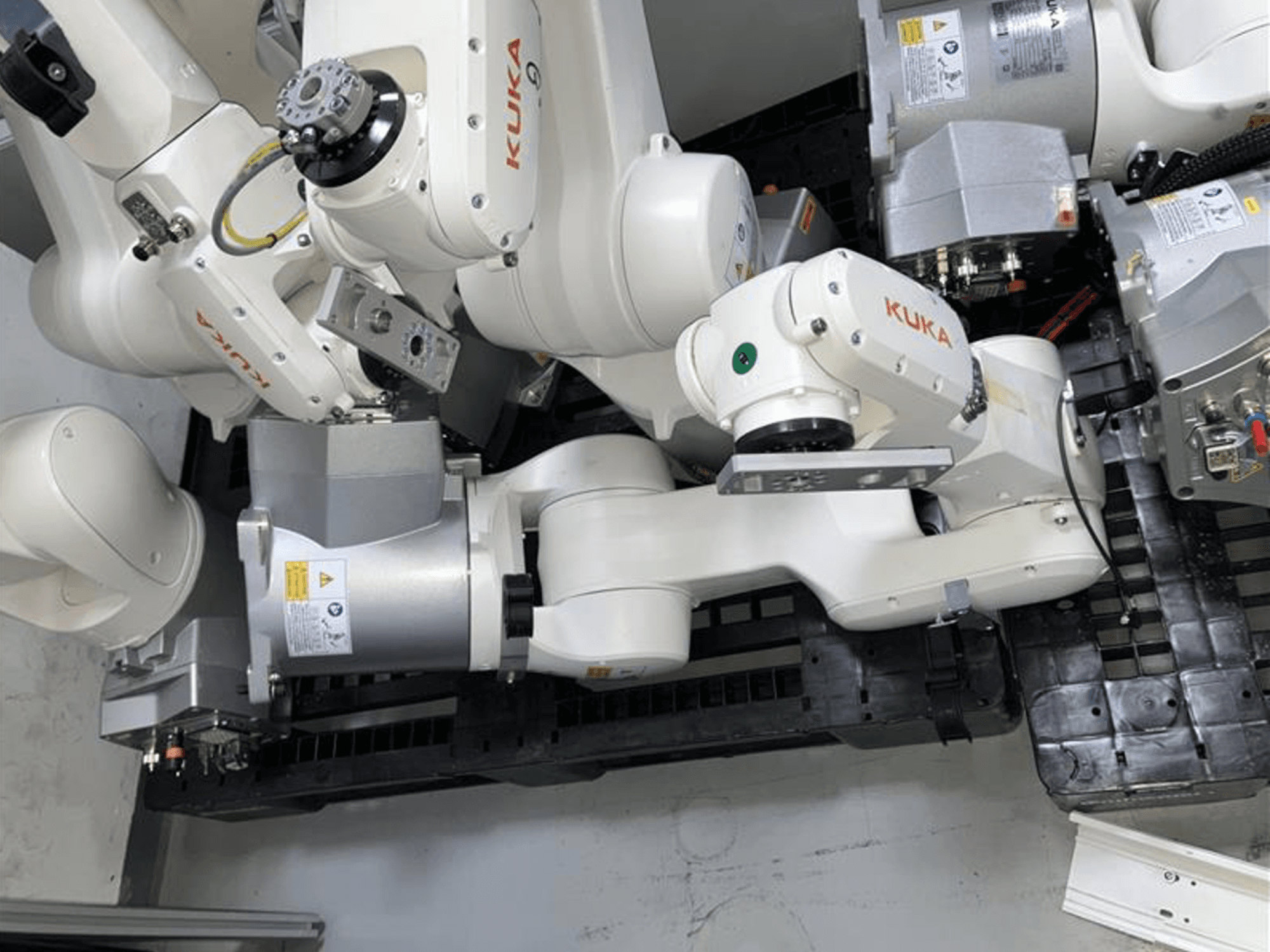 Bras robotique KUKA KR 6 R900 CR en vue de dessus, doté de plusieurs articulations et moteurs, monté sur une base noire avec des câbles.