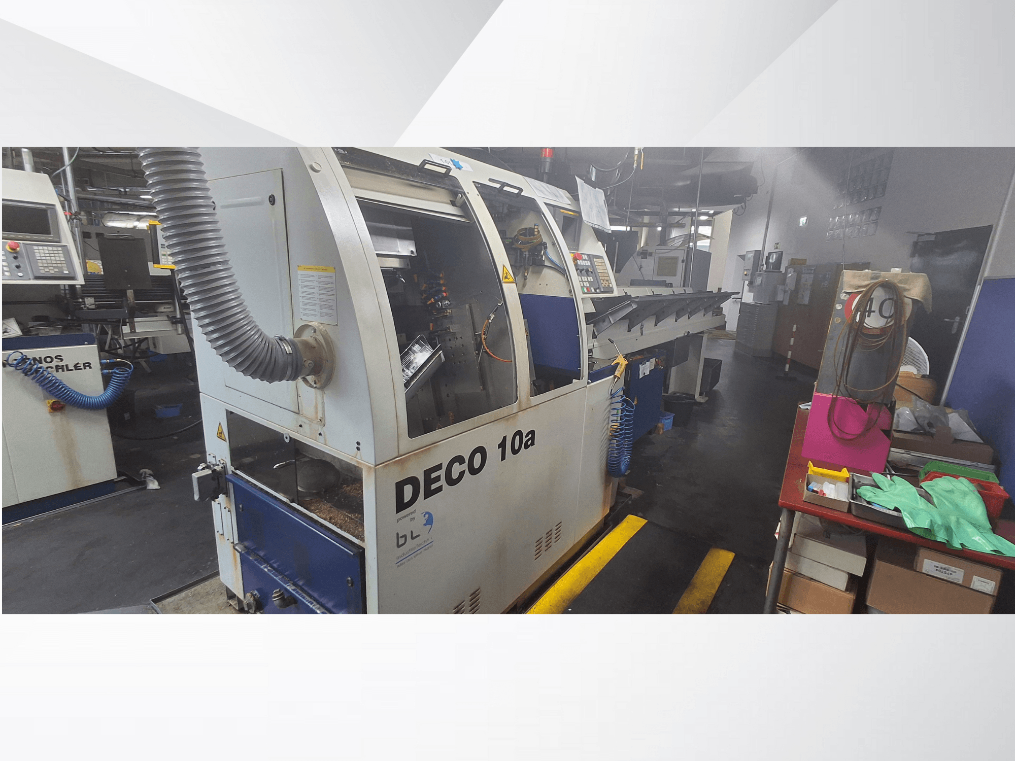 Machine CNC DECO 10a dans un atelier, vue de face ; elle comporte un panneau de commande et un système d'extraction des poussières, avec un établi à proximité.