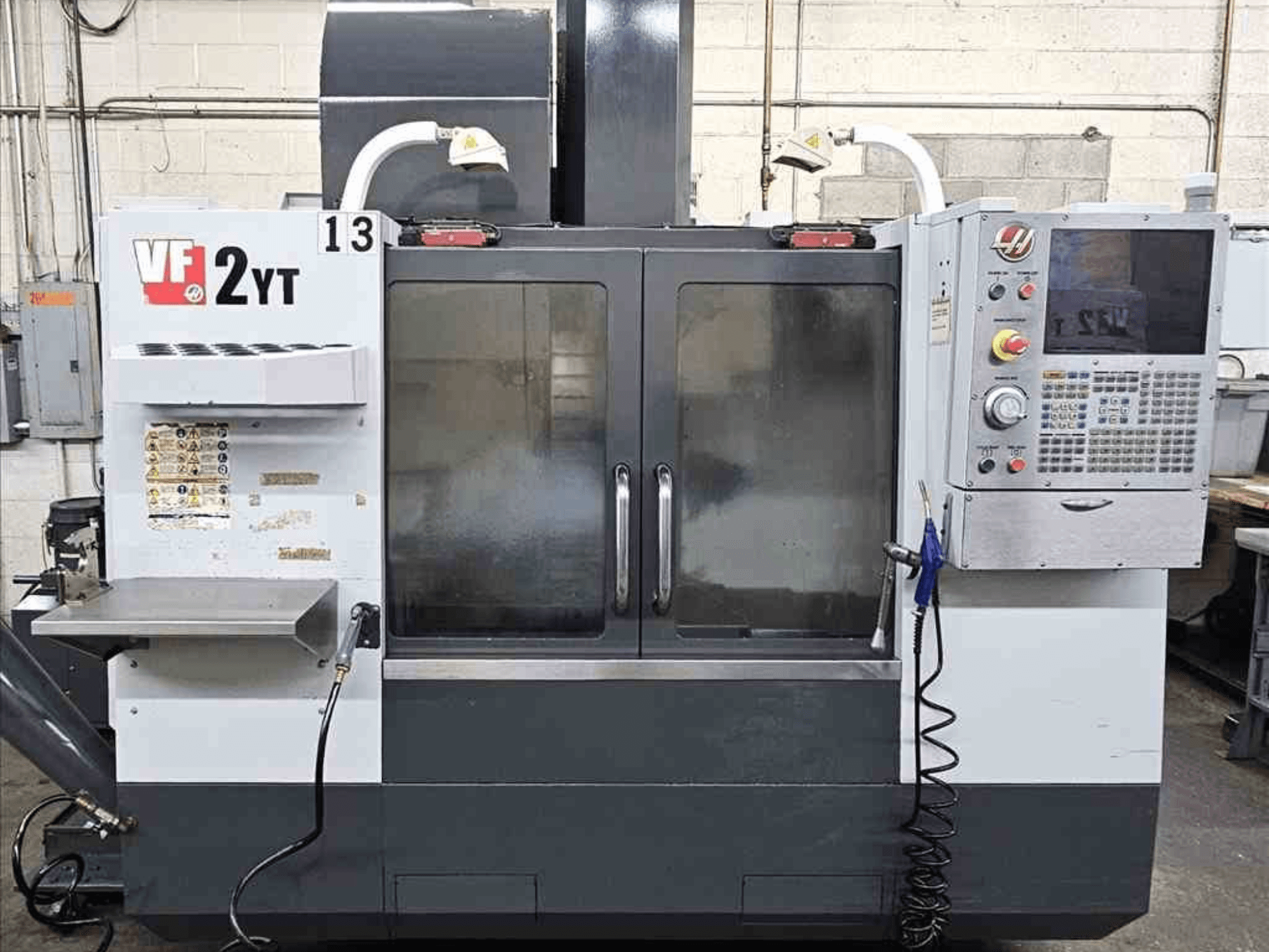 Vue avant d'un centre d'usinage vertical HAAS VF-2YT, montrant le panneau de commande et les portes vitrées.
