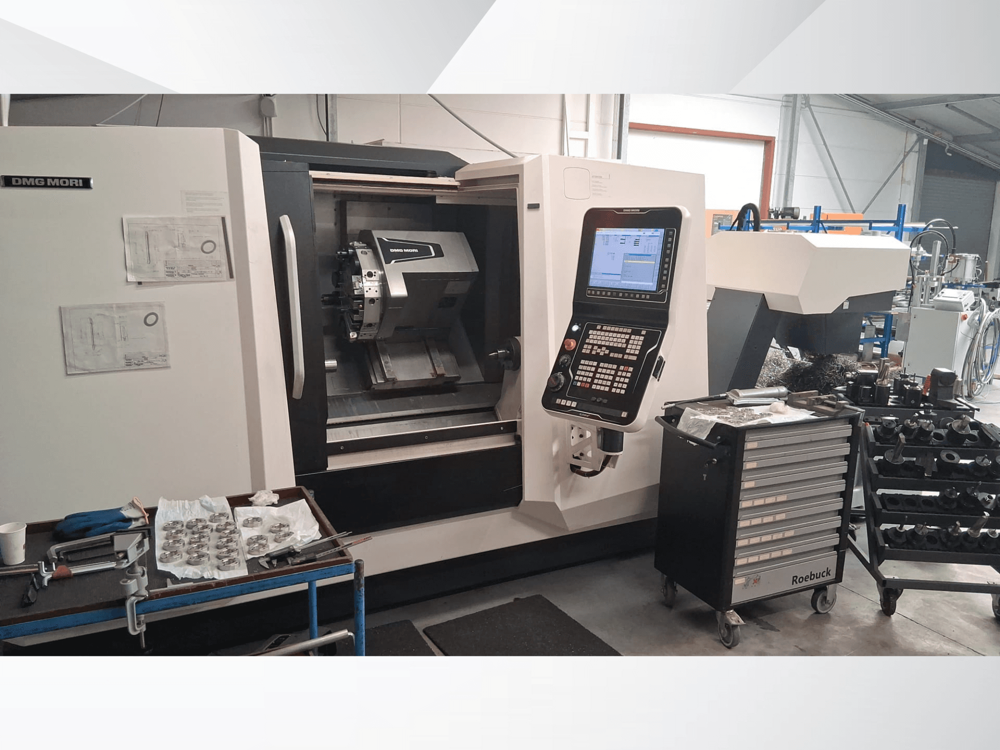 Tour horizontal DMG MORI CLX450 vu de face, avec panneau de commande, zone de travail, outils et pièces métalliques.