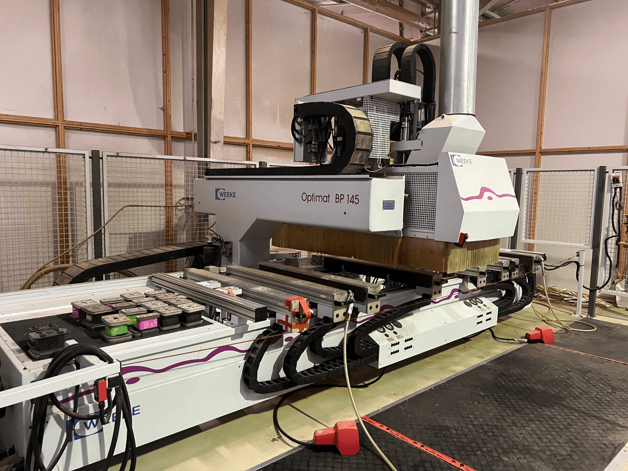 WEEKE Optimat BP 145 dans une usine, présentant une machine CNC avec des boutons de commande et des câbles, vue de côté.