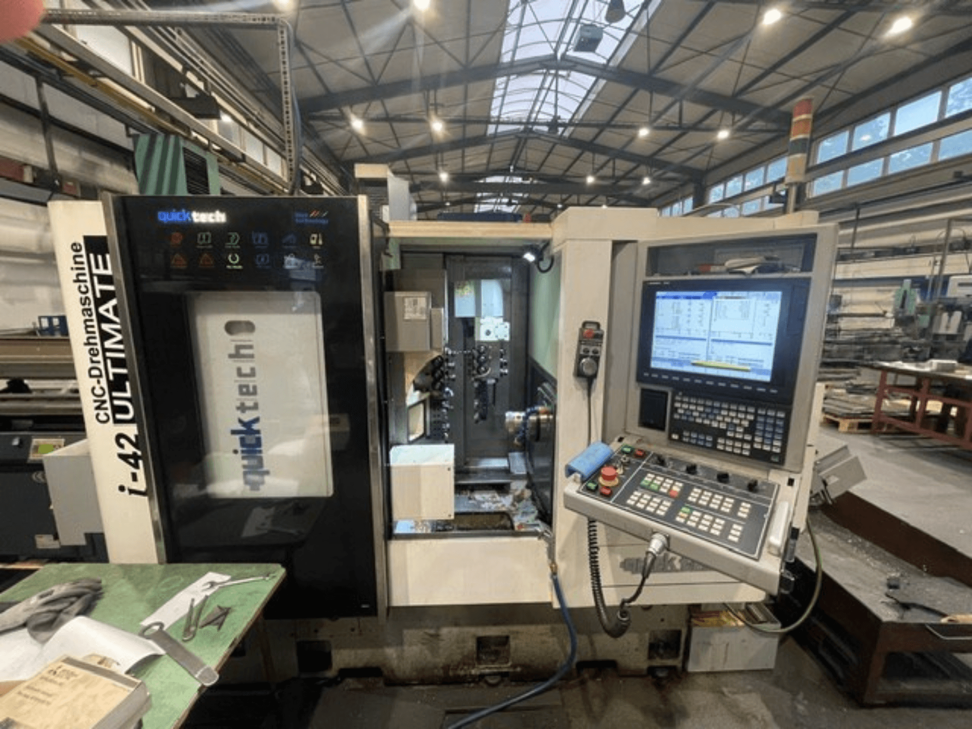 Quick-Tech I-42U Swiss Type Turning Machine, vue de face, montrant le panneau de commande et l'interface CNC dans un atelier.