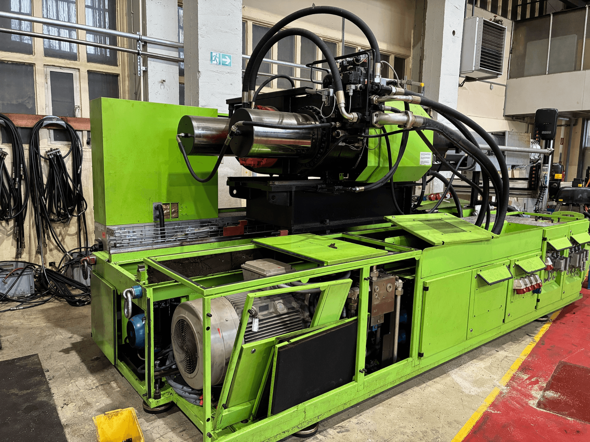 Machine industrielle verte avec système hydraulique, vue de face, montrant le moteur et les différents panneaux de commande.