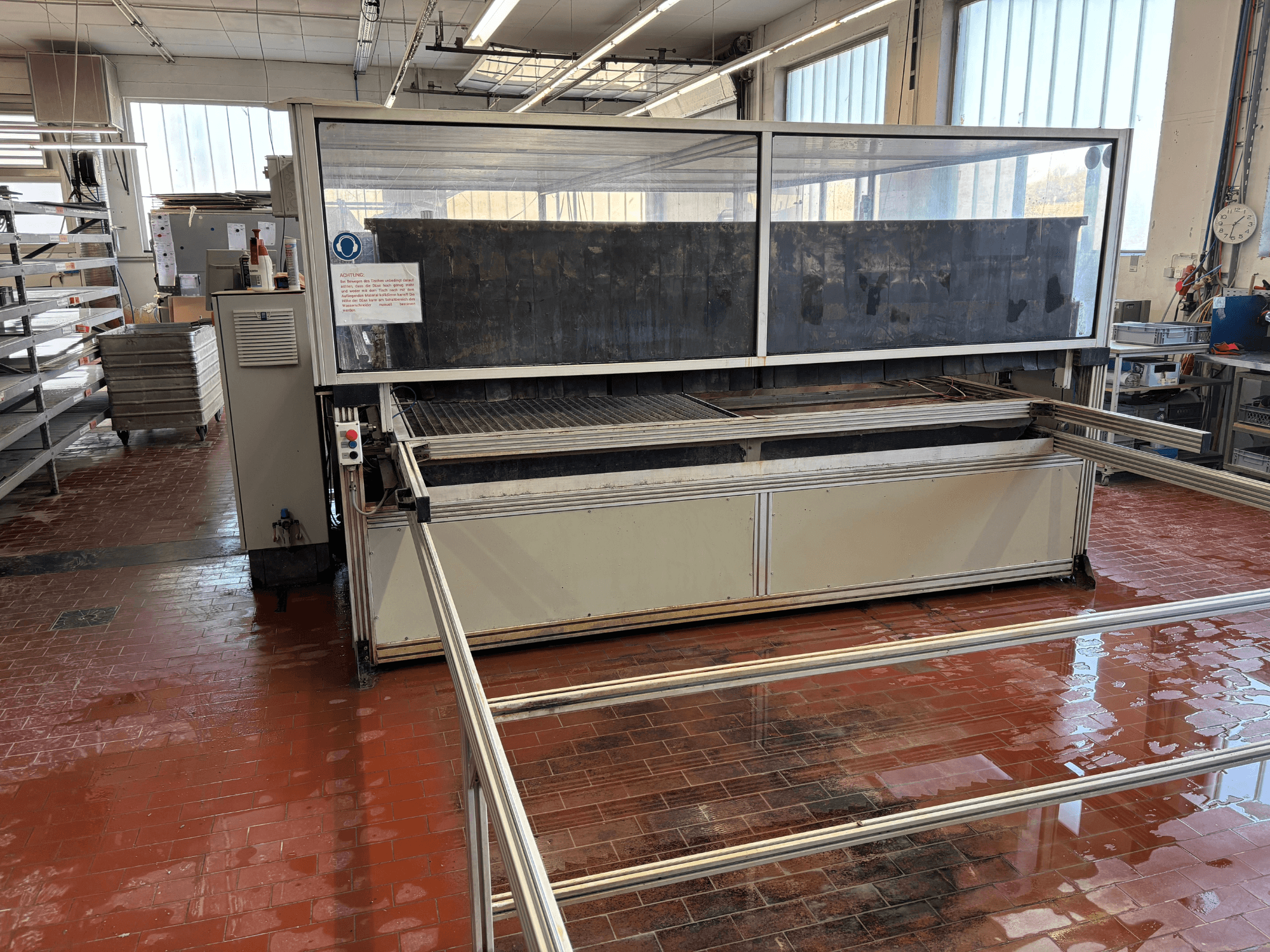 Machine de découpe au jet d'eau EXPERT SYSTEMTECHNIK « cutExpert variojet » dans un atelier, vue de face, dotée d'un grand capot transparent.