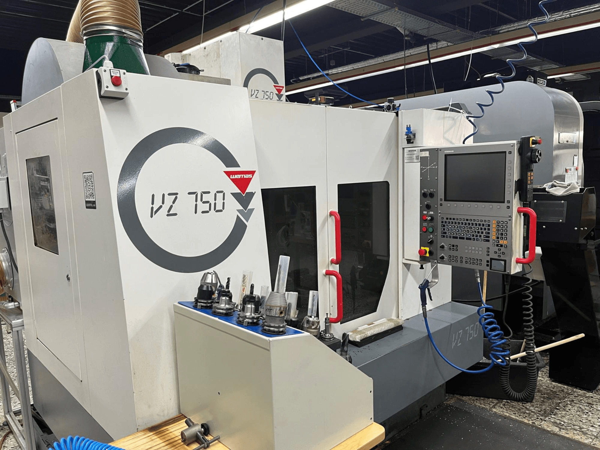 Le centre d'usinage vertical WEMAS VZ 750, vue de face, présente le panneau de commande, les porte-outils et les détails de conception de la machine.