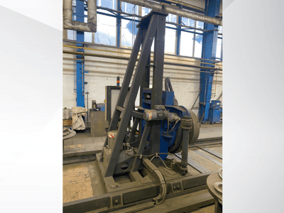 Machine industrielle avec moteur bleu et châssis métallique, vue de face dans un atelier.