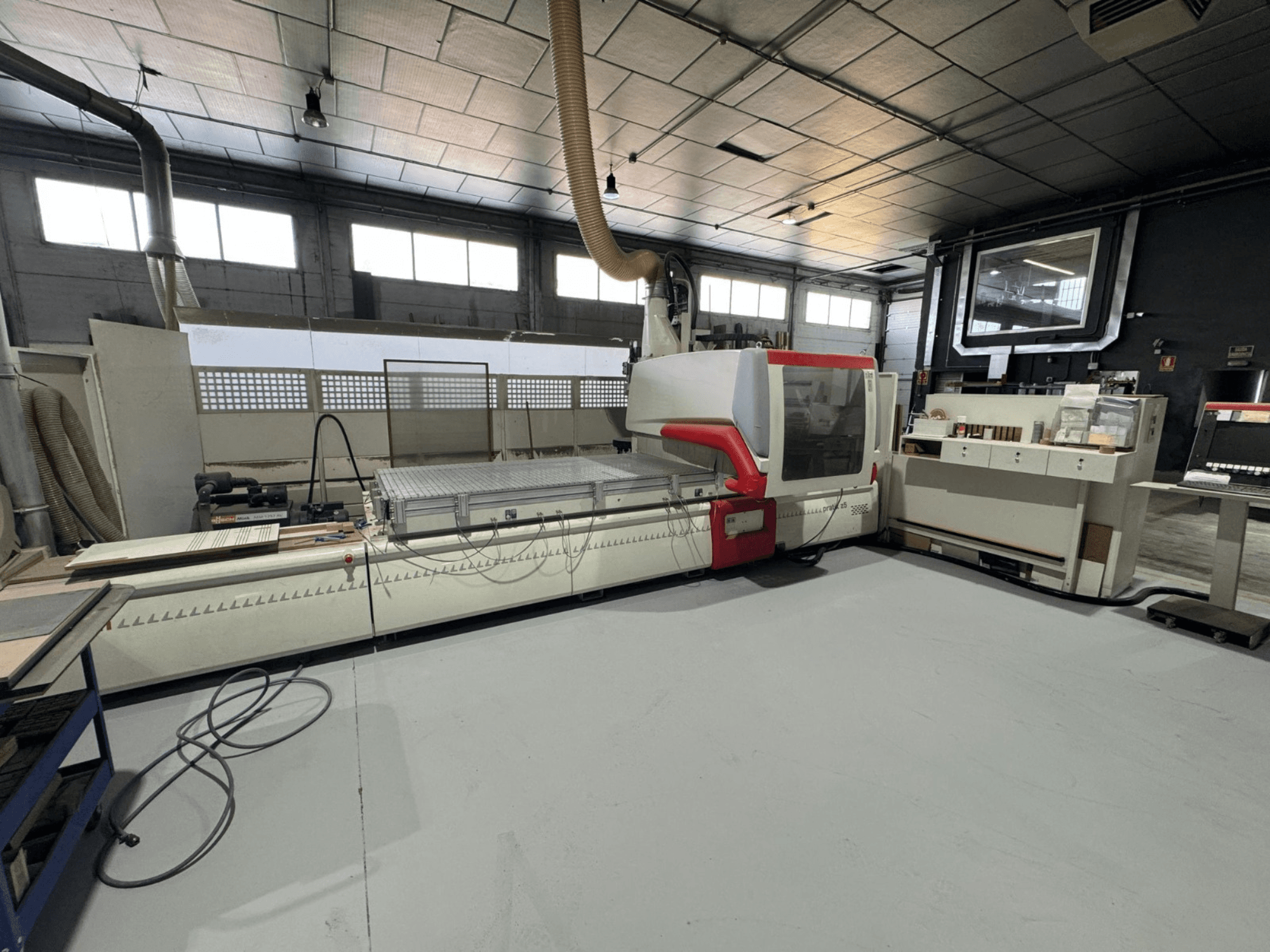 Machine CNC dans un atelier, vue de face avec accents rouges, équipée d'un panneau de commande et d'une surface de travail, pour la découpe de précision.