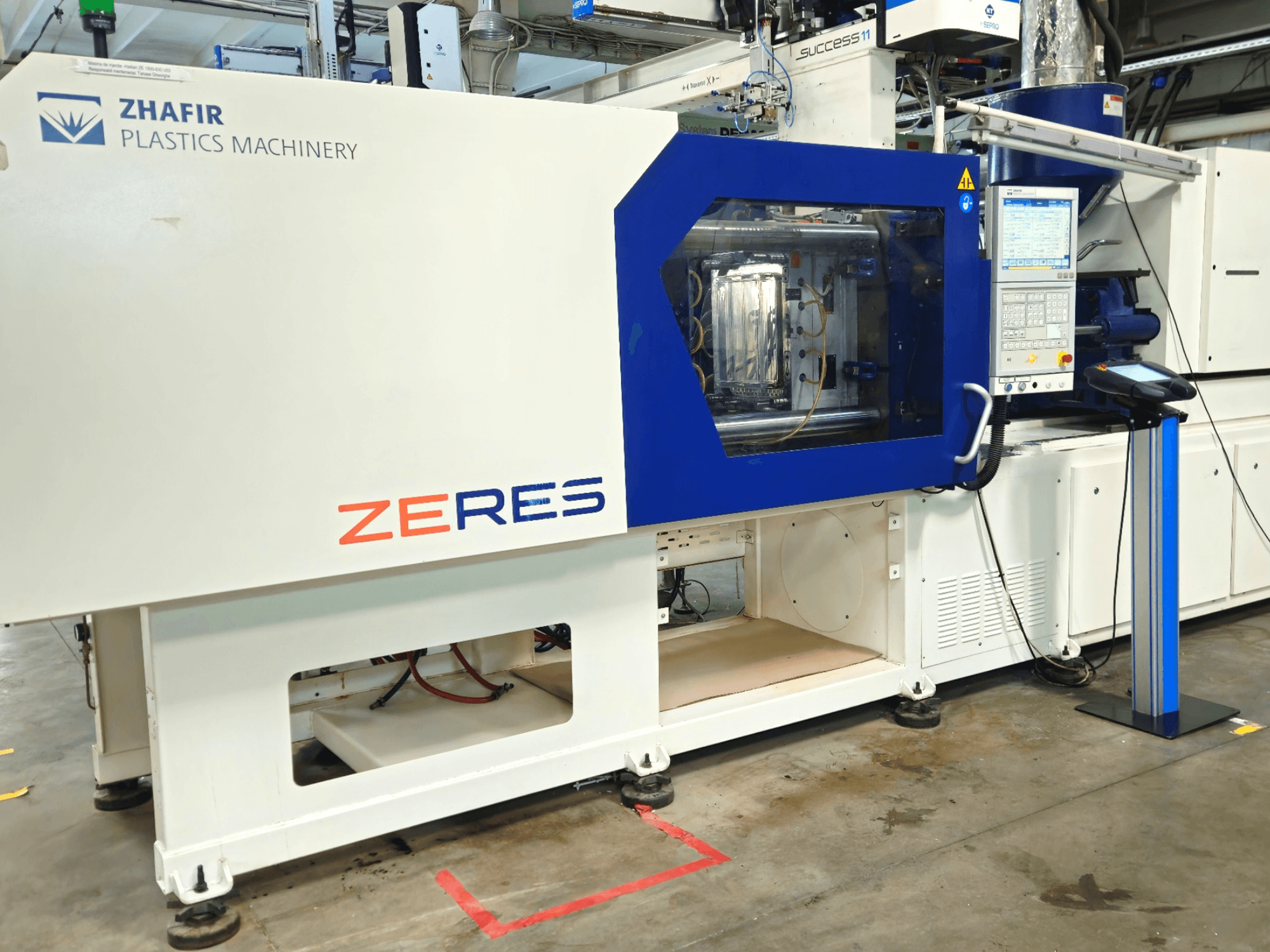 Machine de moulage par injection Zhafir Zeres vue de face, avec panneau de commande et zone de moulage transparente.
