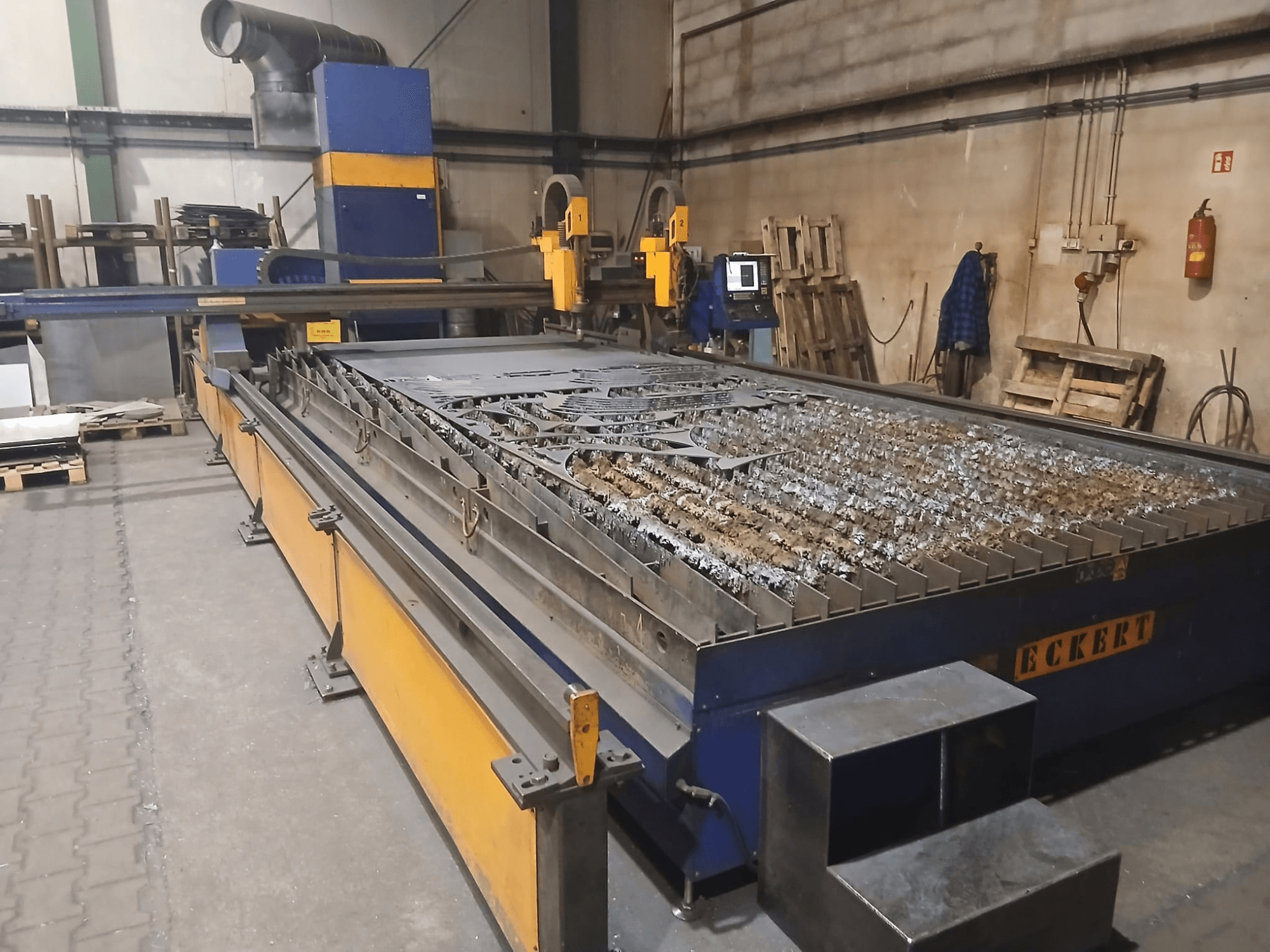 Machine de découpe au plasma ECKERT JANTAR 2 vue de face, dotée d'une grande table de découpe sur laquelle sont posées des pièces métalliques, ainsi que des commandes de fonctionnement.