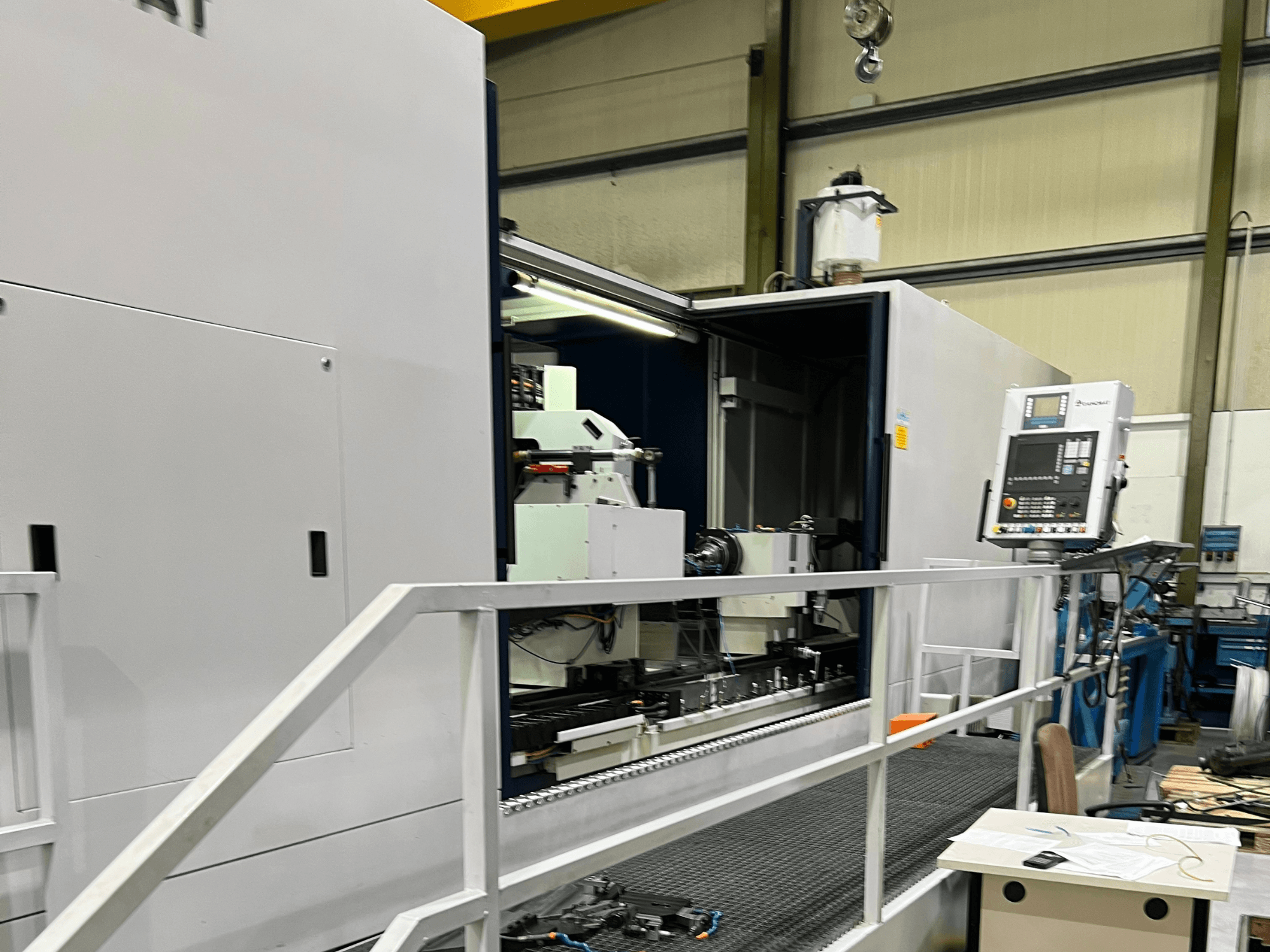 Centre d'usinage CNC avec vue latérale ouverte, montrant les commandes, le porte-outil et le composant principal à l'intérieur. Les détails de la marque ne sont pas visibles.