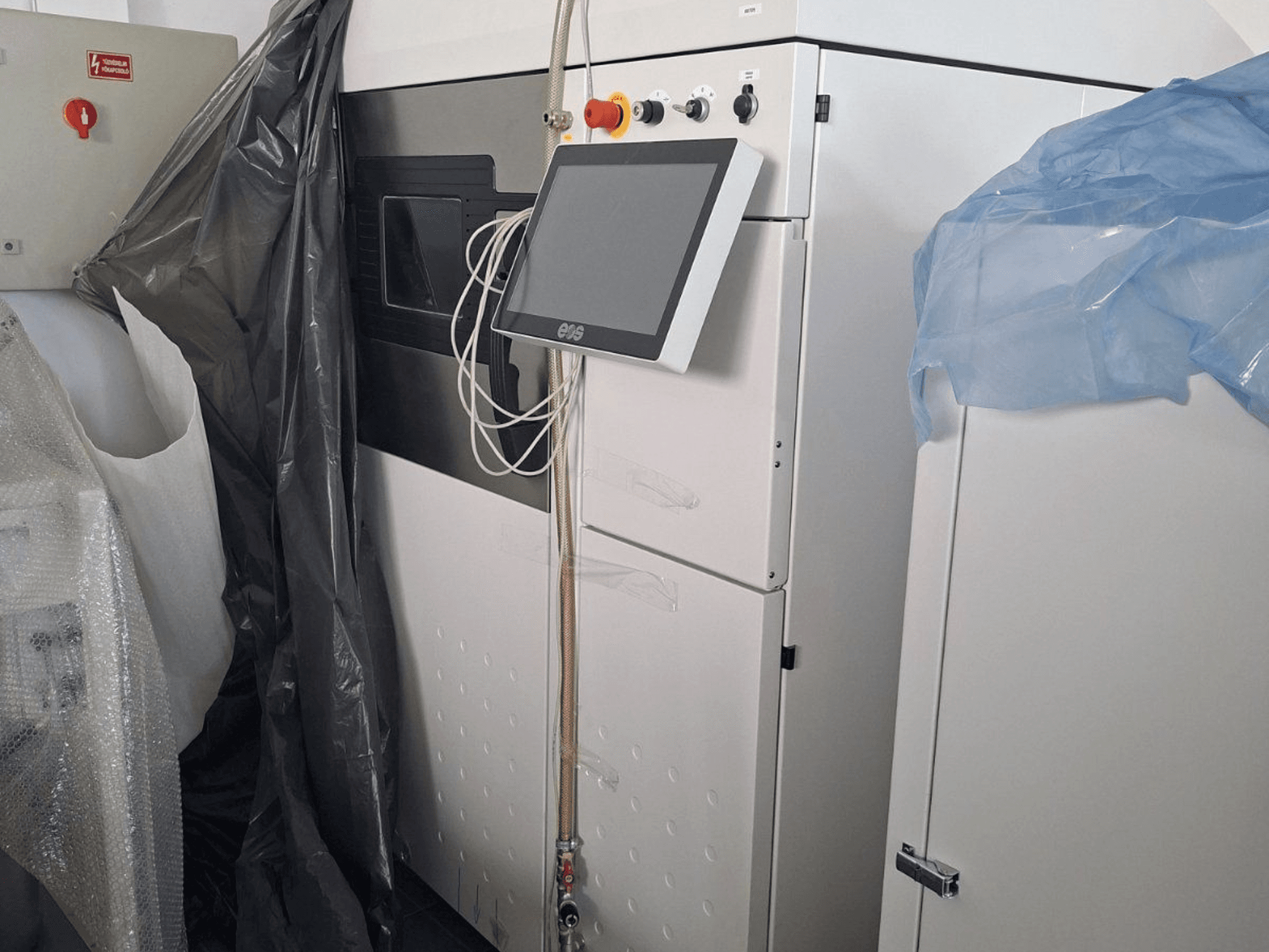 Vue avant de l'imprimante 3D métal EOS M 290, avec son écran tactile, son panneau de commande et ses protections.