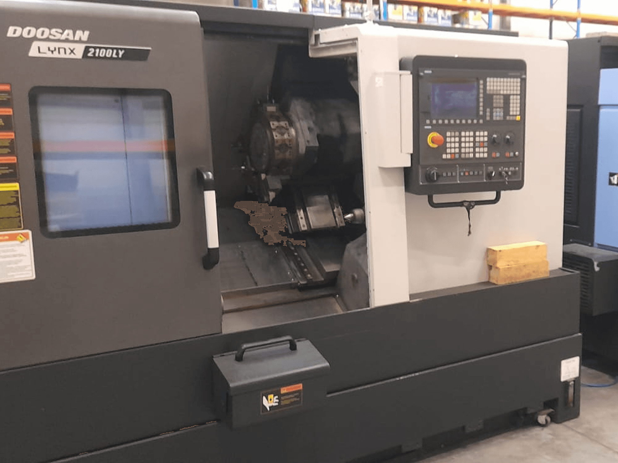 Tour CNC Doosan Lynx 2100LY, vue de face montrant le panneau de commande, le porte-outil et l'espace de travail intérieur ; étiquettes techniques visibles.