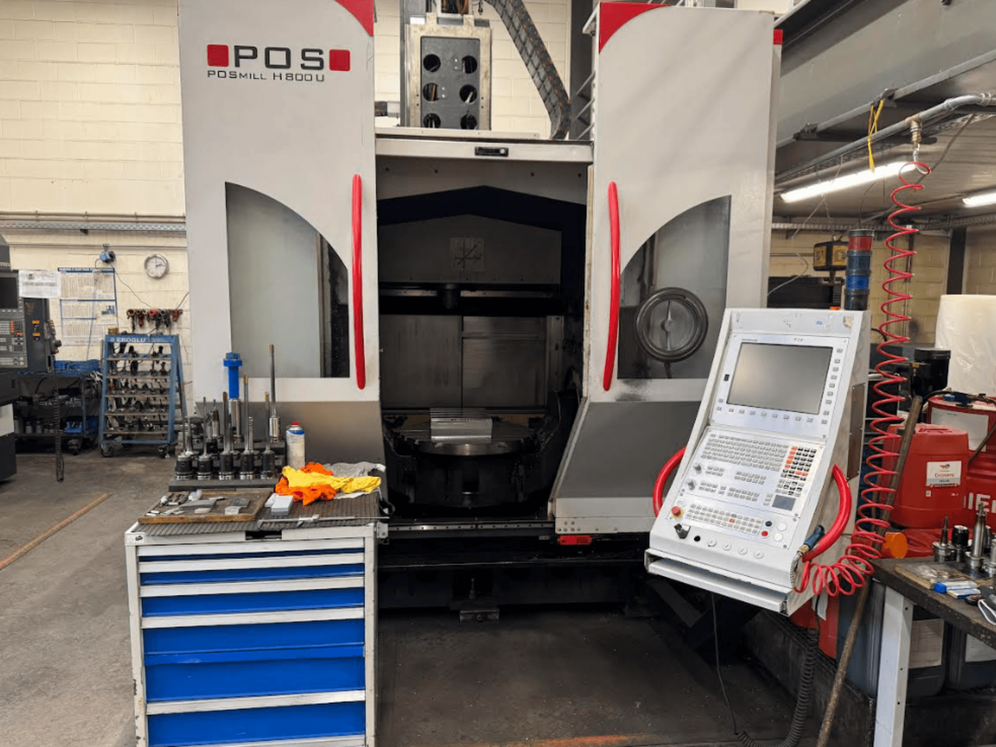 Machine CNC POSMILL H800 U vue de face, montrant le panneau de commande et la zone de travail avec les outils et l'équipement à proximité.