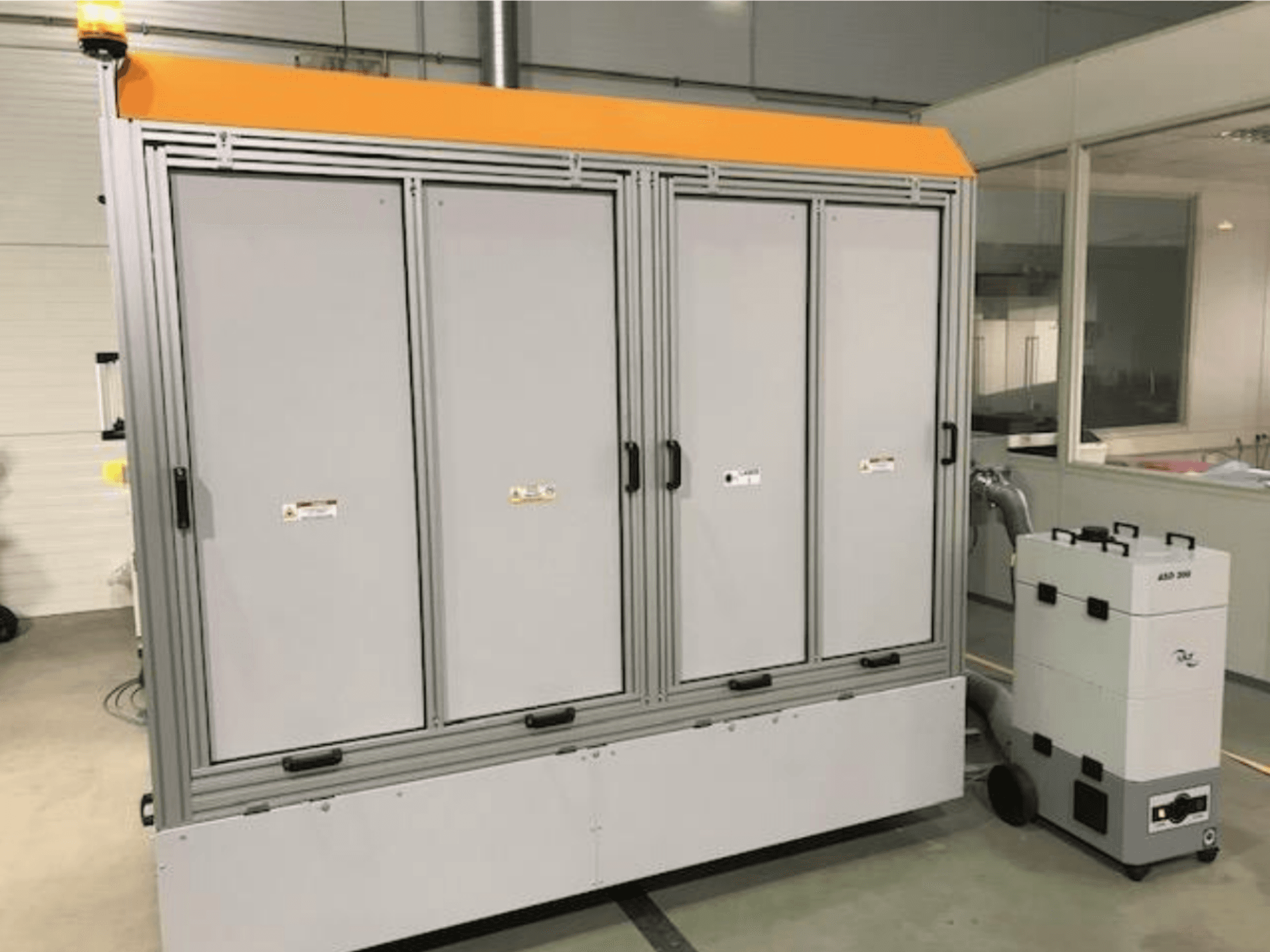 Machine de découpe laser à fibre 4JET Pearl M, vue de face, avec le voyant de sécurité, le panneau de commande et l'unité d'extraction connectée visibles.