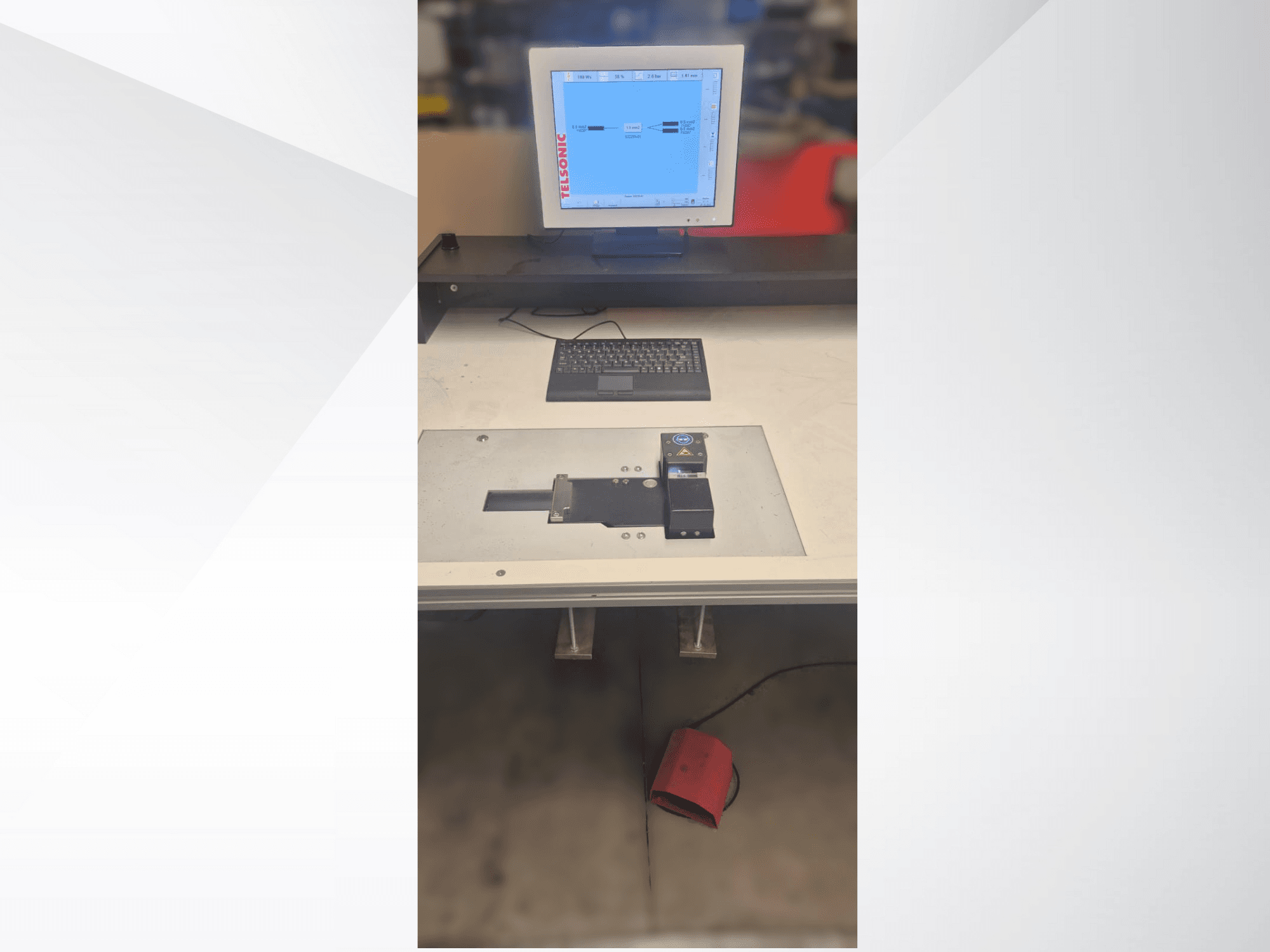 Vue de haut en bas d'un poste de test avec un écran d'ordinateur, un clavier et un panneau de commande comportant un bouton et un voyant vert.