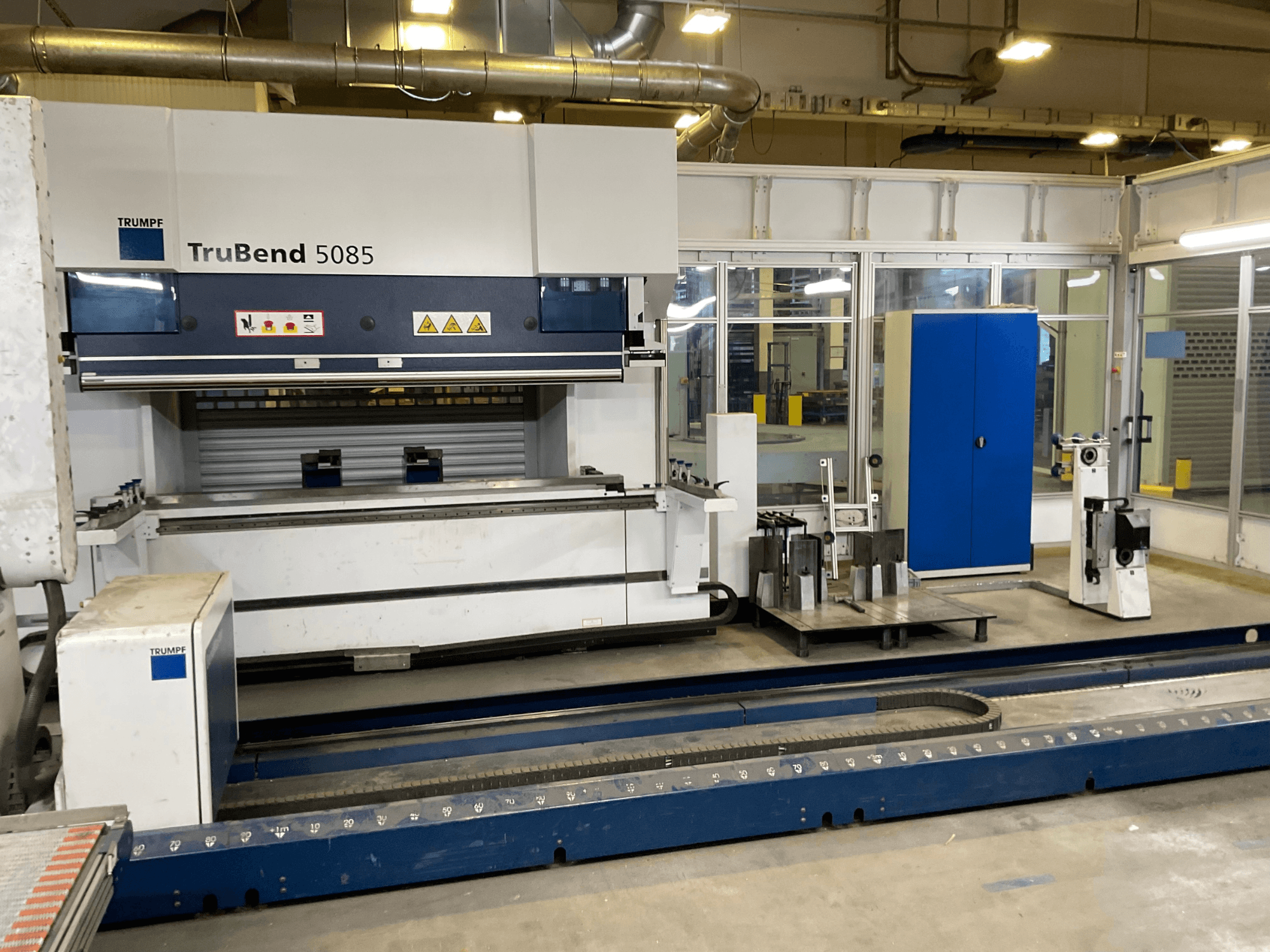 TruBend 5085 de TRUMPF, vue latérale d'une grande cintreuse de métaux avec panneau de commande et divers outils à côté.