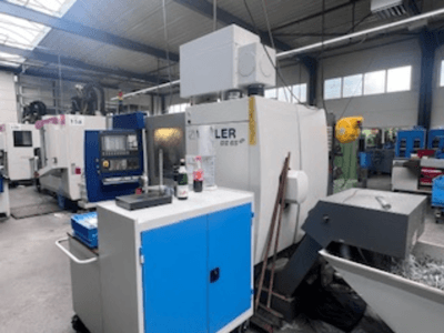 Atelier industriel équipé d'un centre d'usinage Heller, vue de face montrant les outils, les commandes et l'équipement environnant.