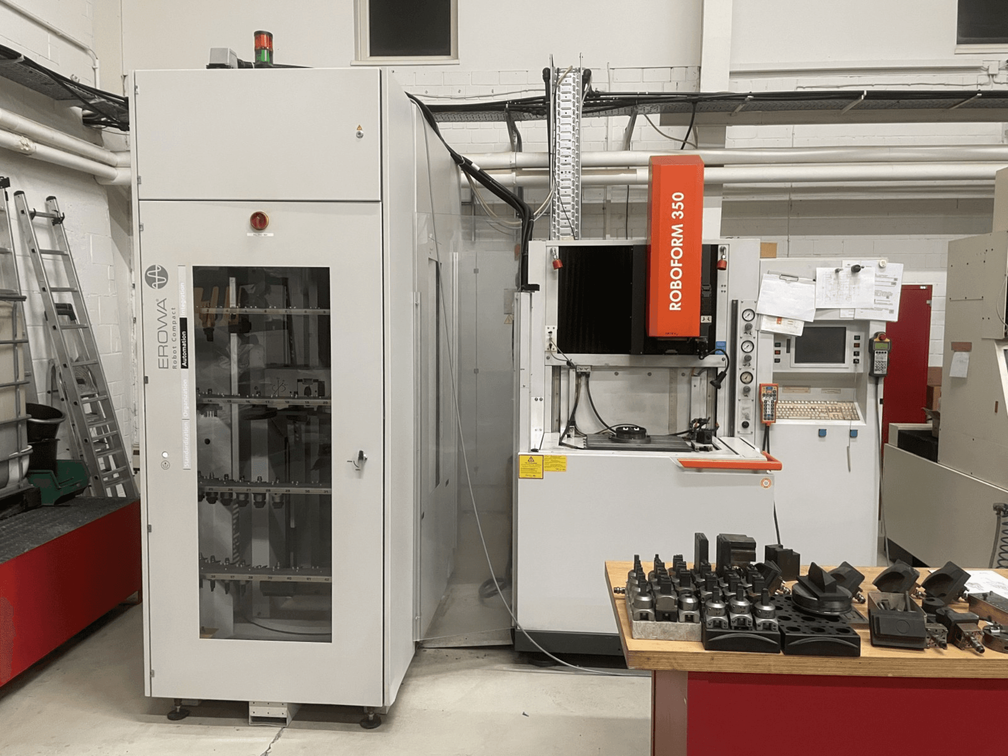 Machine d'électroérosion par enfonçage CHARMILLES Roboform 350, vue de face, avec des outils présentés sur une table et des équipements adjacents.