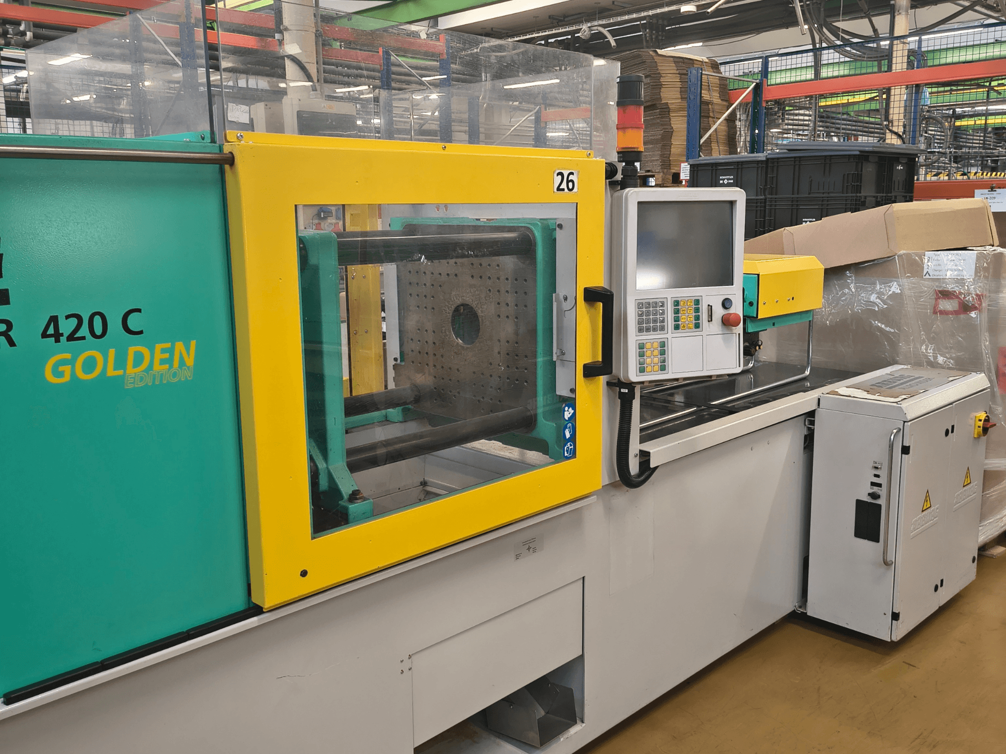 Machine de moulage par injection, ARBURG 420 C Golden Edition, vue de face ; comprend un panneau de commande, une protection de sécurité claire et un espace de travail environnant.