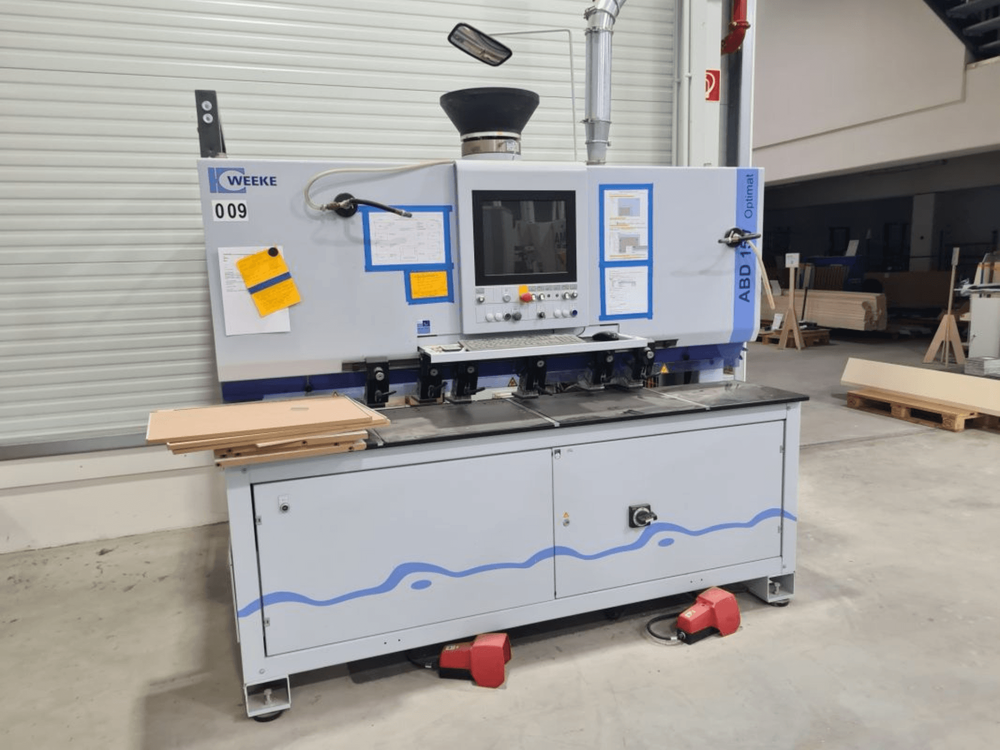 Perceuse multibroche HOMAG WEEKE OPTIMAT ABD150, vue de face, montrant les commandes et les panneaux de bois empilés.