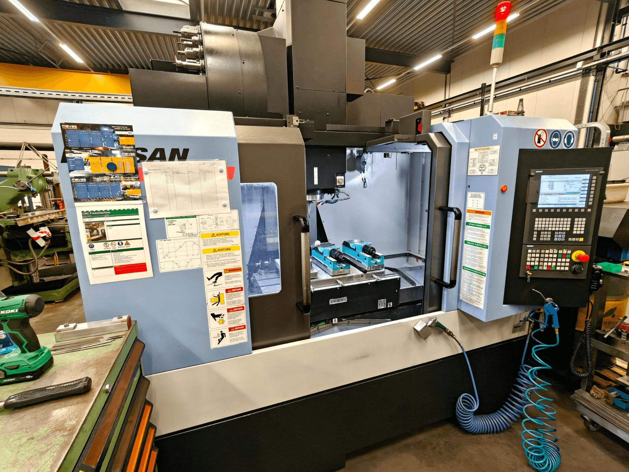 Centre d'usinage vertical DOOSAN DNM 400 II dans un atelier, avec commandes, porte-outils et signalisation de sécurité, vue de face.