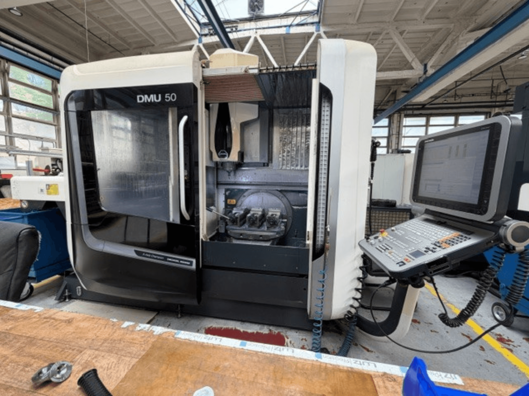 Centre d'usinage vertical DMG MORI DMU 50 de 3e génération, vu de face, avec la porte ouverte, le panneau de commande CNC visible et l'espace de travail à l'intérieur.
