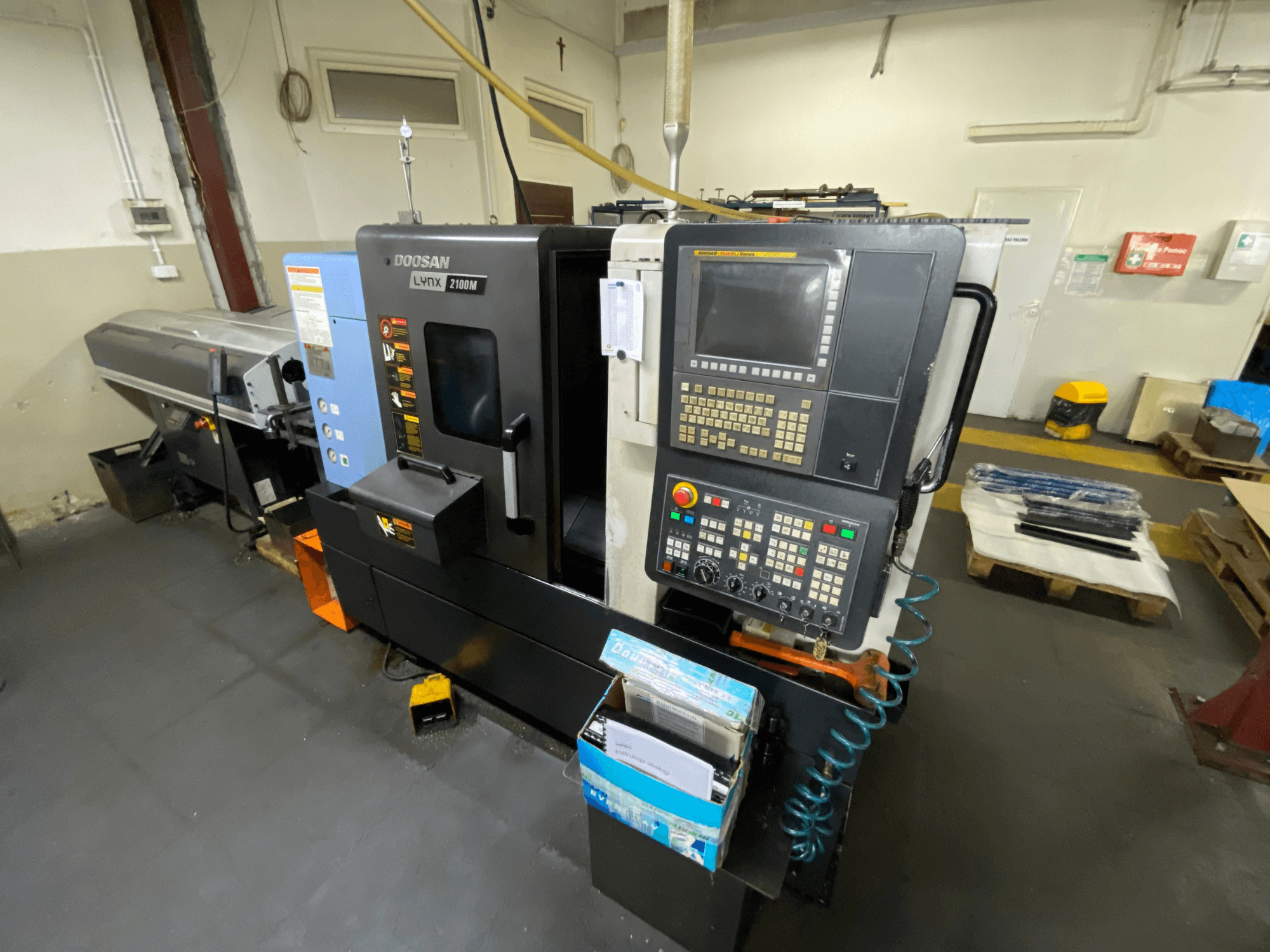 Tour horizontal DOOSAN LYNX 2100MA vu de profil, avec le panneau de commande, les outils et la zone de travail.