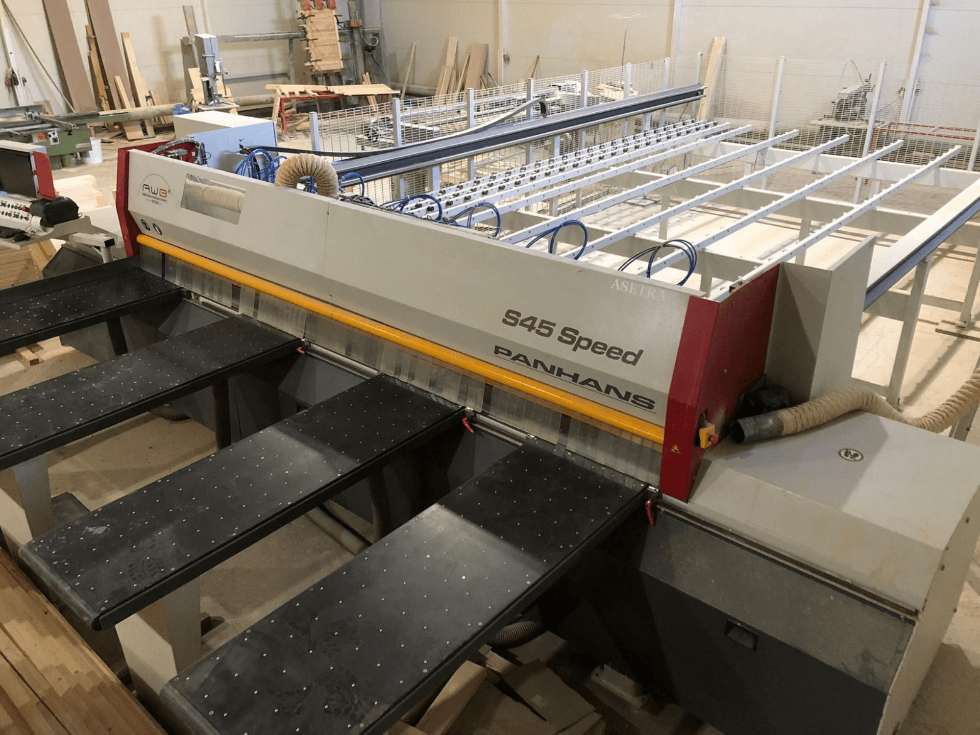 Vue latérale d'une scie à panneaux PANHANS S45 Speed, dotée d'une configuration à cinq tables et d'un panneau de commande visible avec aspiration de la poussière.