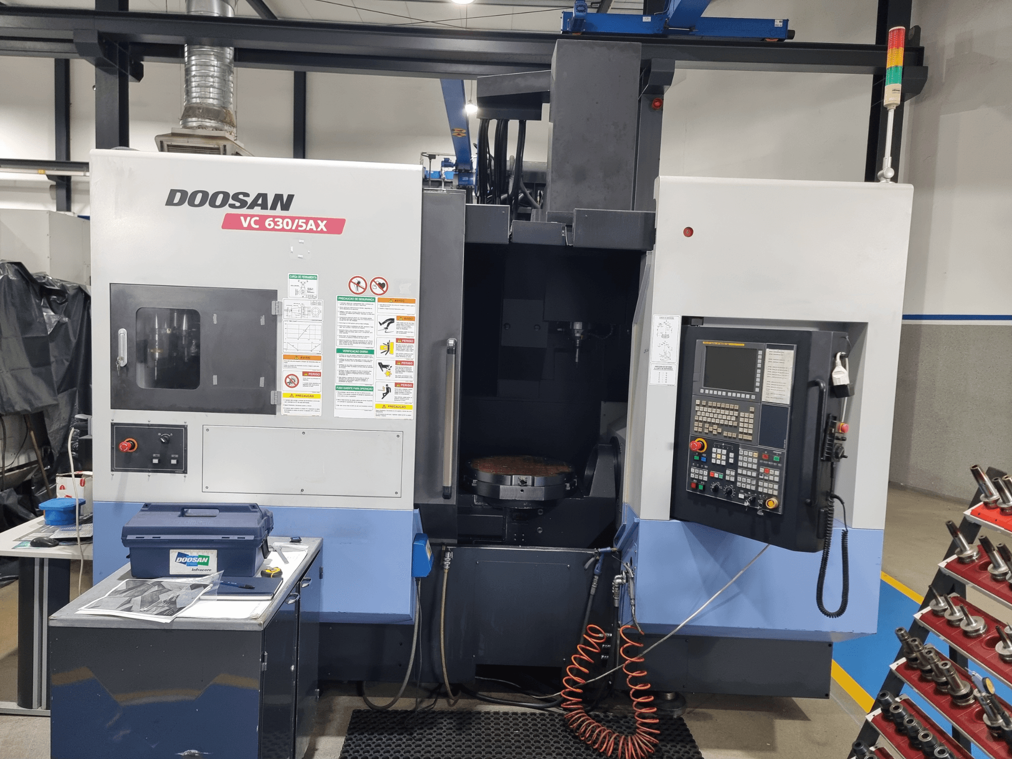 Centre d'usinage universel DOOSAN VC 630/5AX, vue de face présentant le panneau de commande, la zone d'usinage et les dispositifs de sécurité.