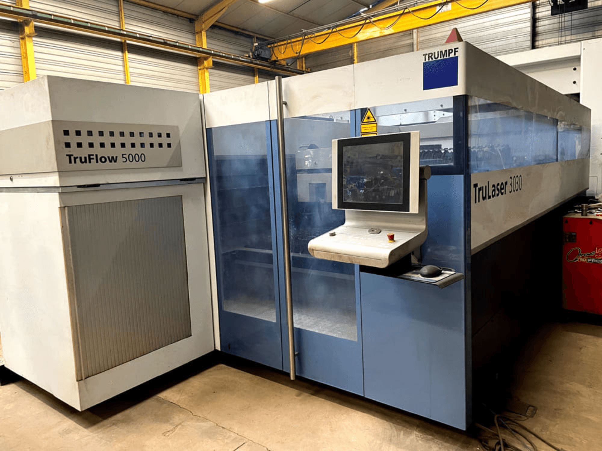 Machine de découpe laser CO₂ TRUMPF TruLaser 3030 vue de face, équipée d'un panneau de commande et d'une unité TruFlow 5000 adjacente.