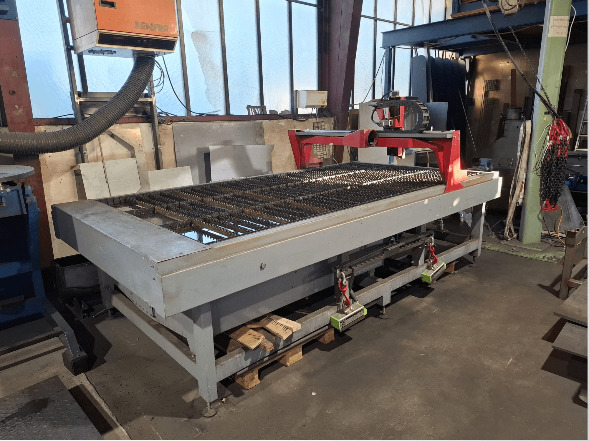 Machine de découpe au plasma PLASMACUT 3015T vue de profil, dotée d'une grande table de découpe à lattes métalliques et d'un châssis rouge.